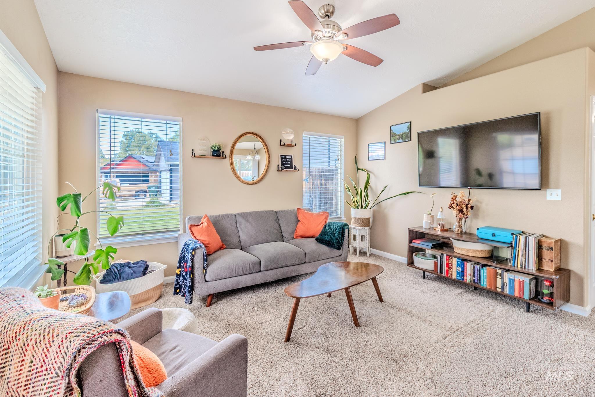 Carpeted living room featuring plenty of natural light, lofted ceiling, and ceiling fan