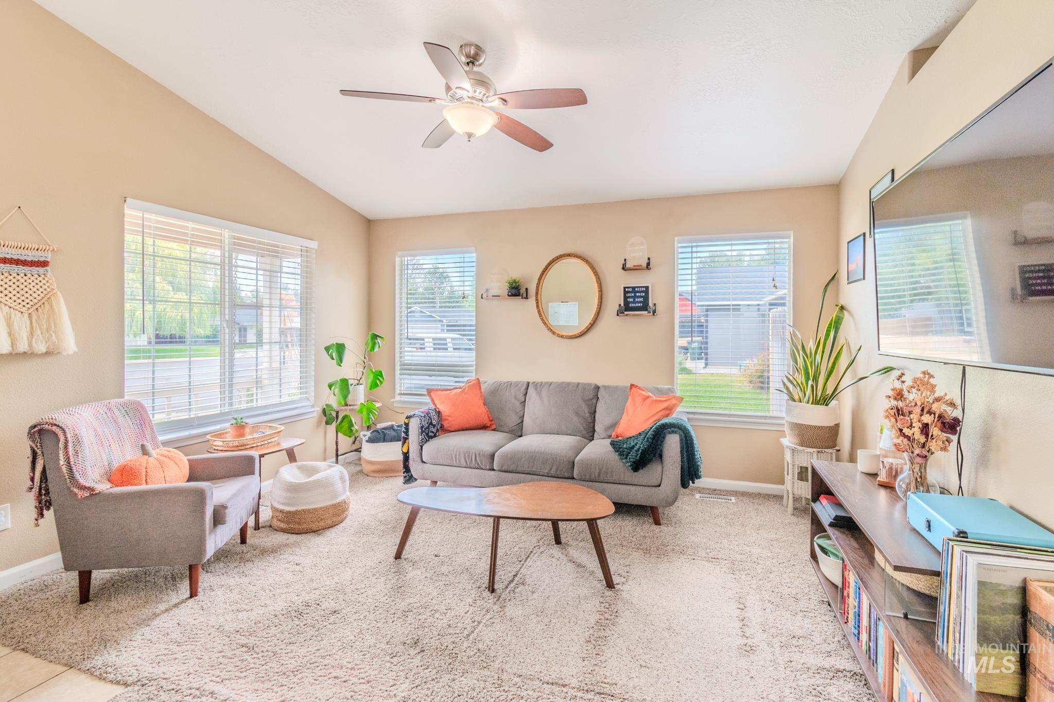 Living room featuring ceiling fan, lofted ceiling, and light colored carpet