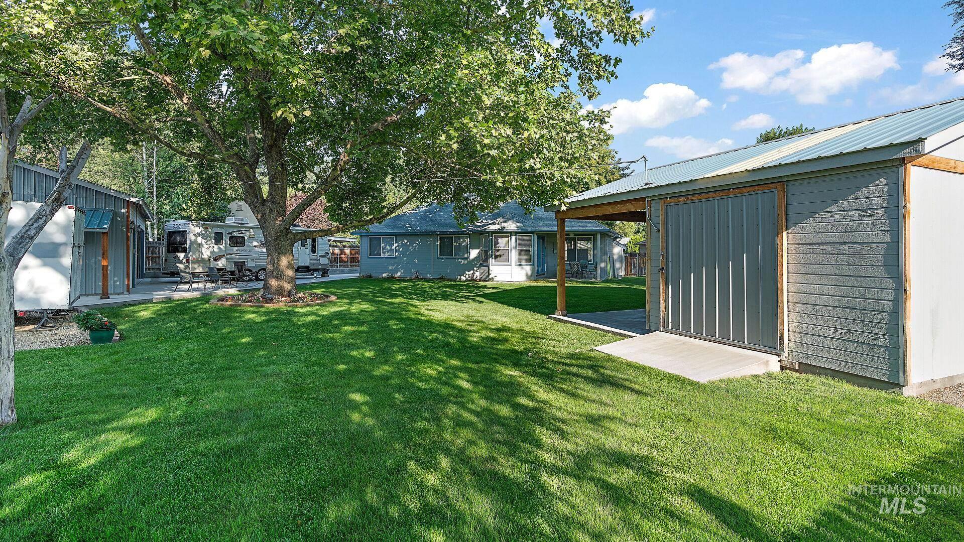 View of green lawn featuring a patio and a shed