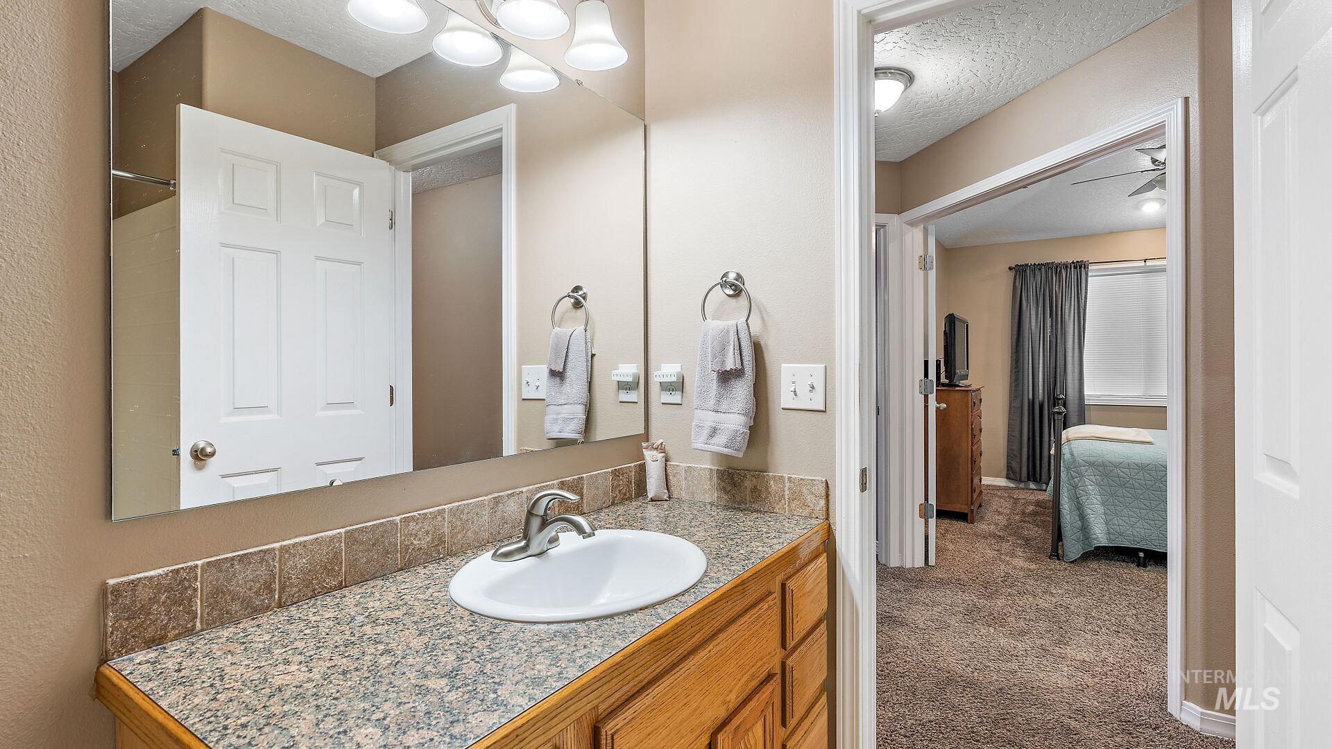 Full bathroom featuring a textured ceiling, vanity, and connected bathroom