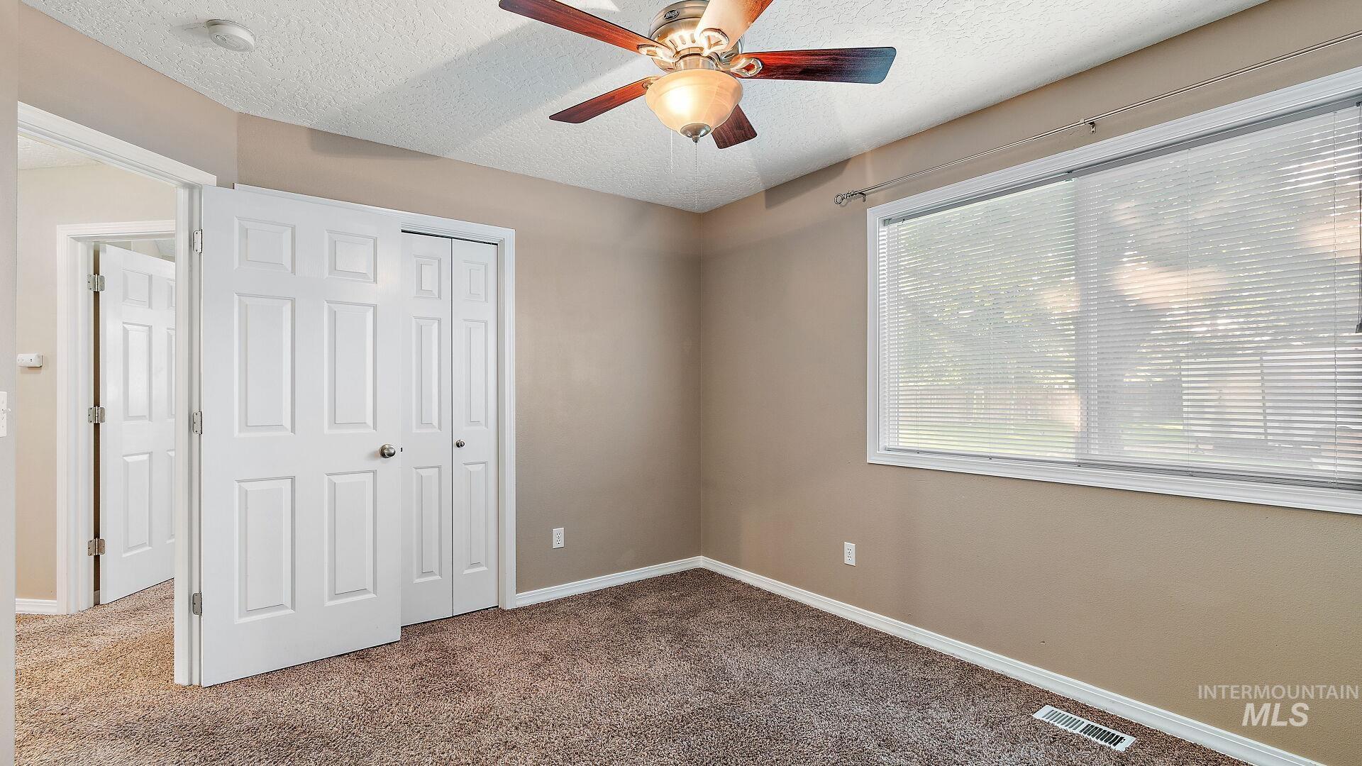 Unfurnished bedroom featuring carpet floors, a textured ceiling, ceiling fan, and a closet