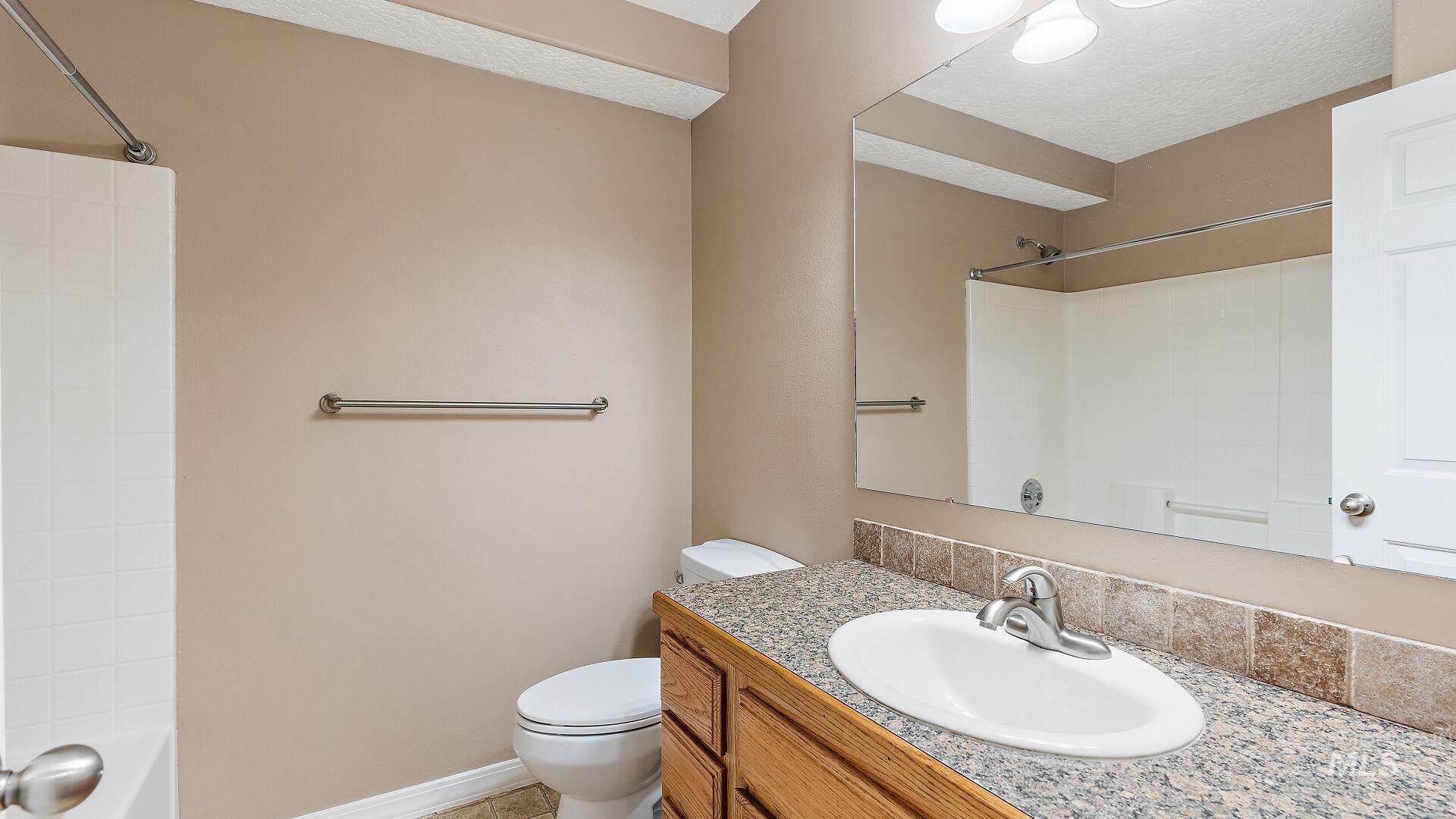 Full bathroom with vanity, tub / shower combination, a textured ceiling, and light tile patterned flooring