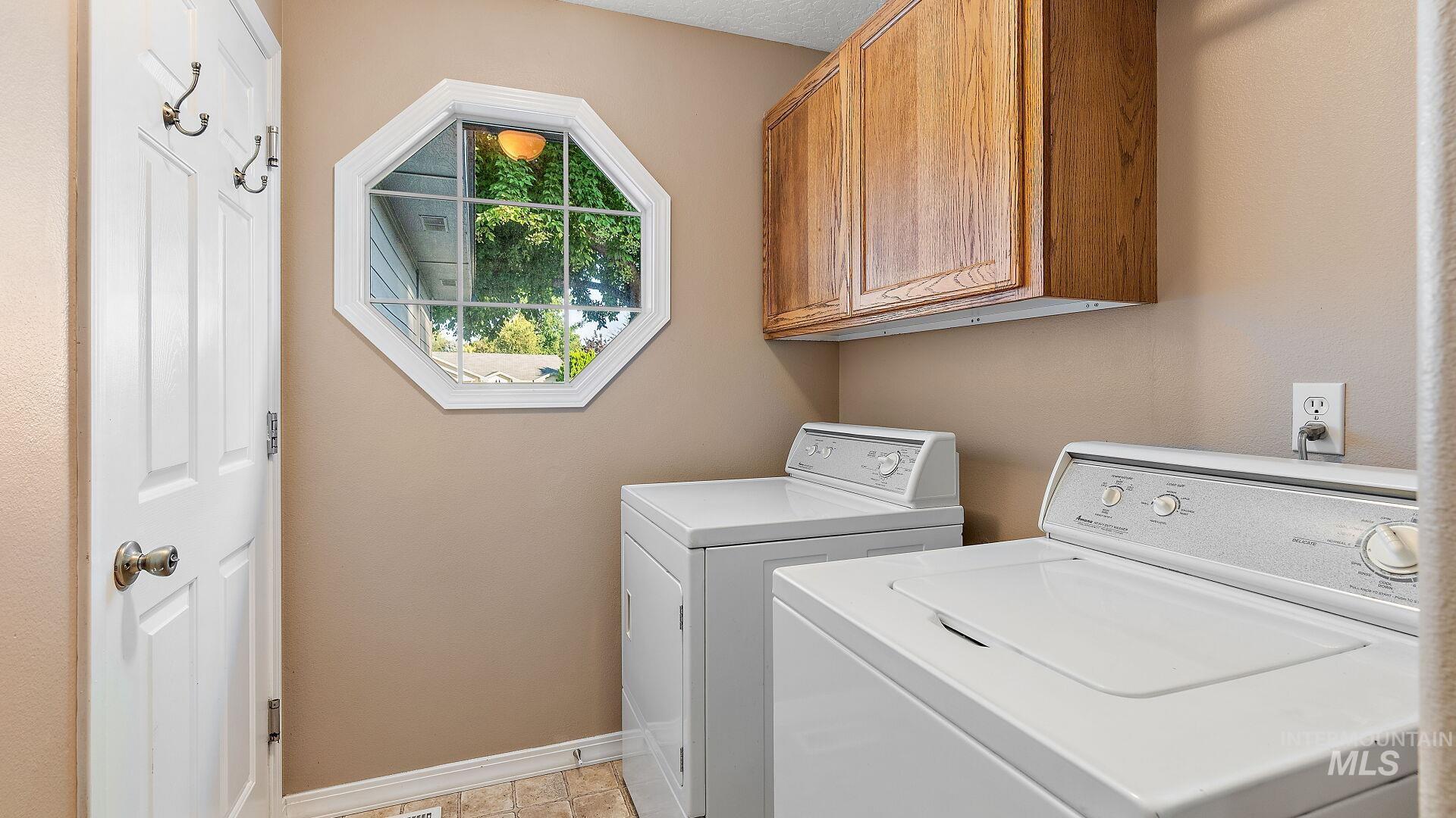 Laundry room featuring cabinet space, washer and clothes dryer, and light tile patterned flooring