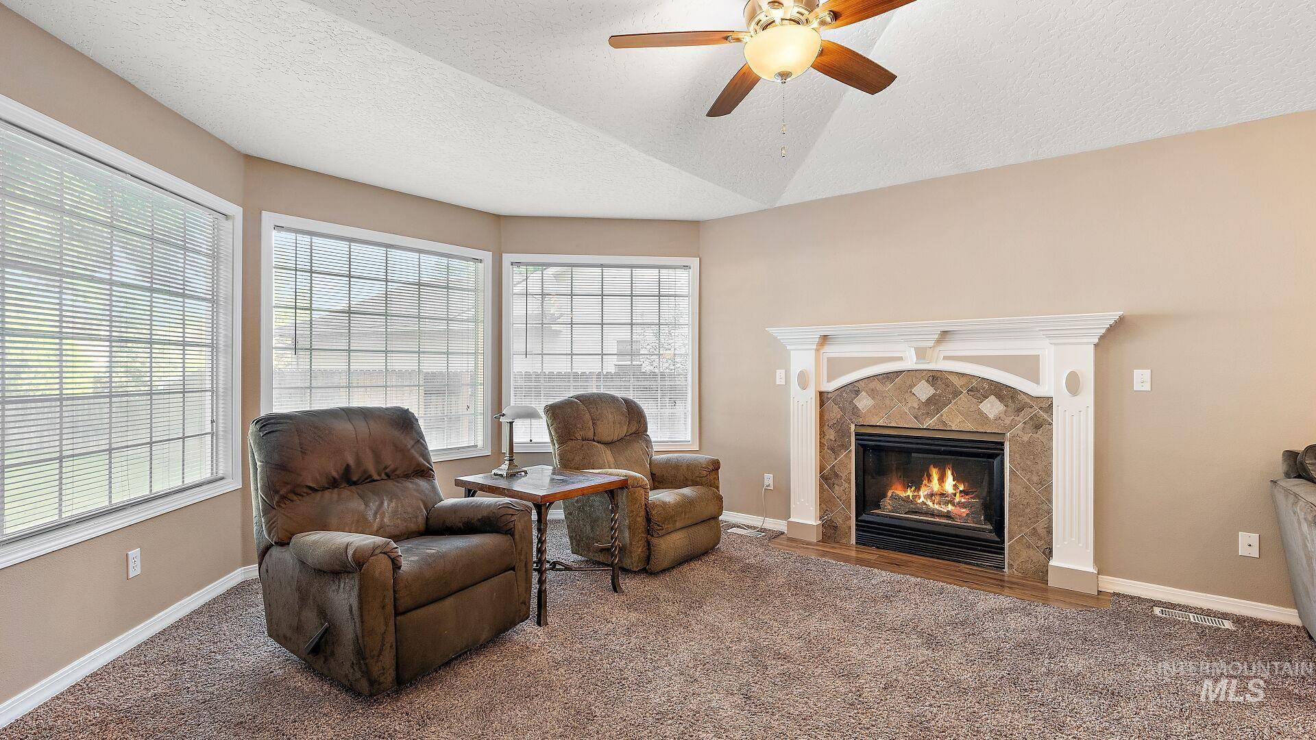 Sitting room with a textured ceiling, carpet, a high end fireplace, and ceiling fan