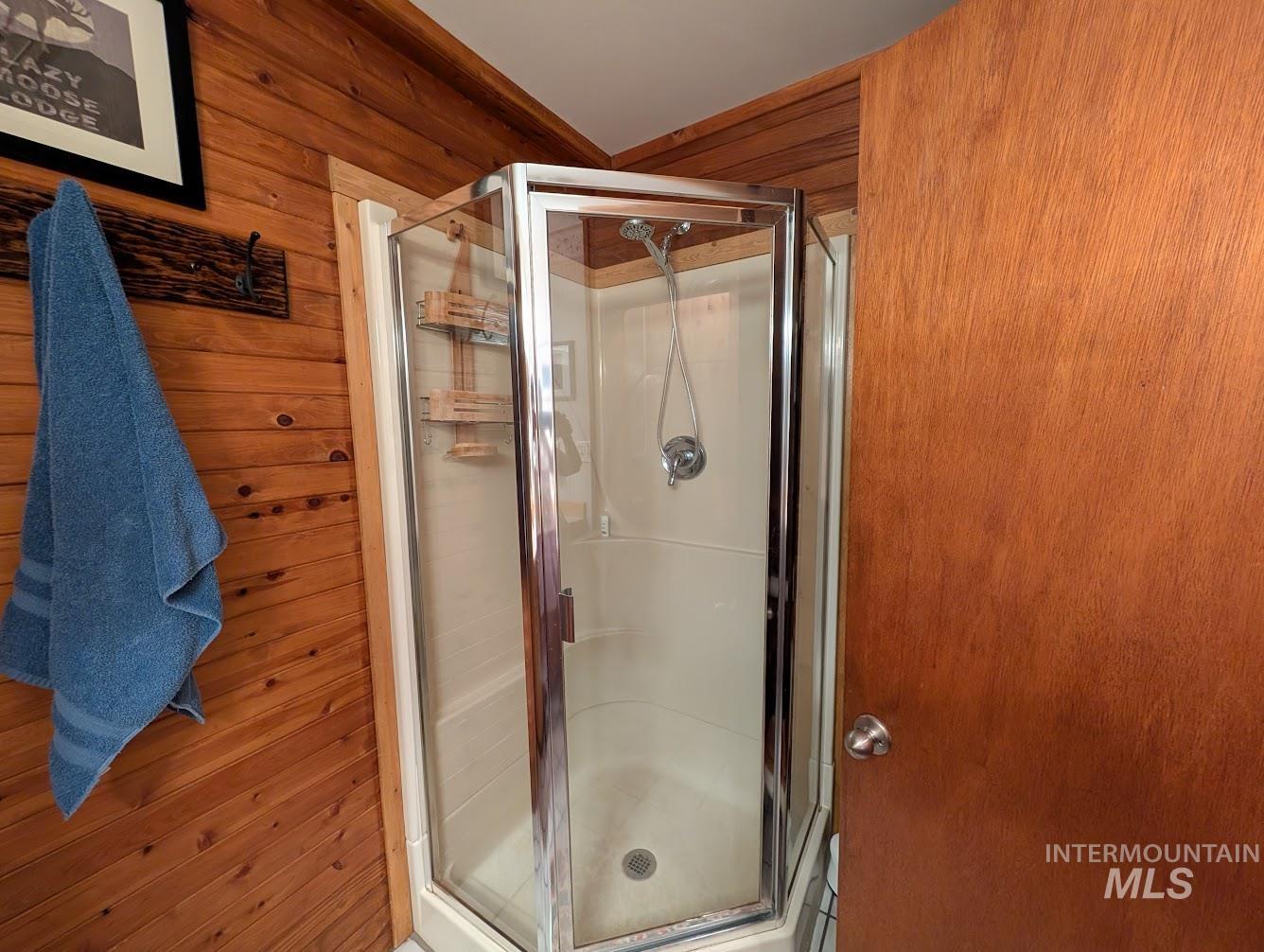 Bathroom featuring wood walls and a shower stall