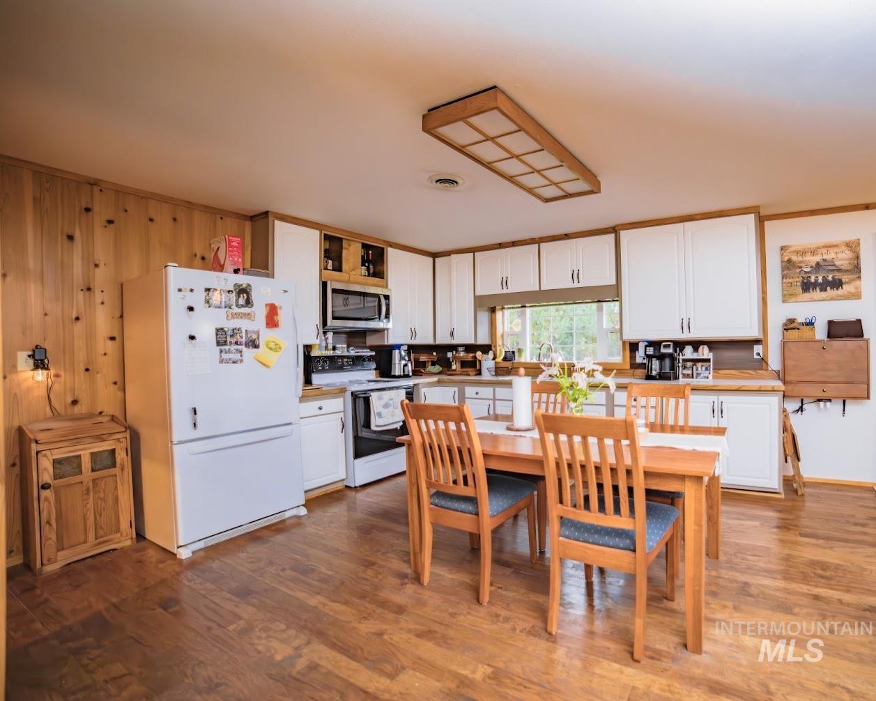 Kitchen featuring white cabinets, white appliances, dark wood-style floors, and ornamental molding