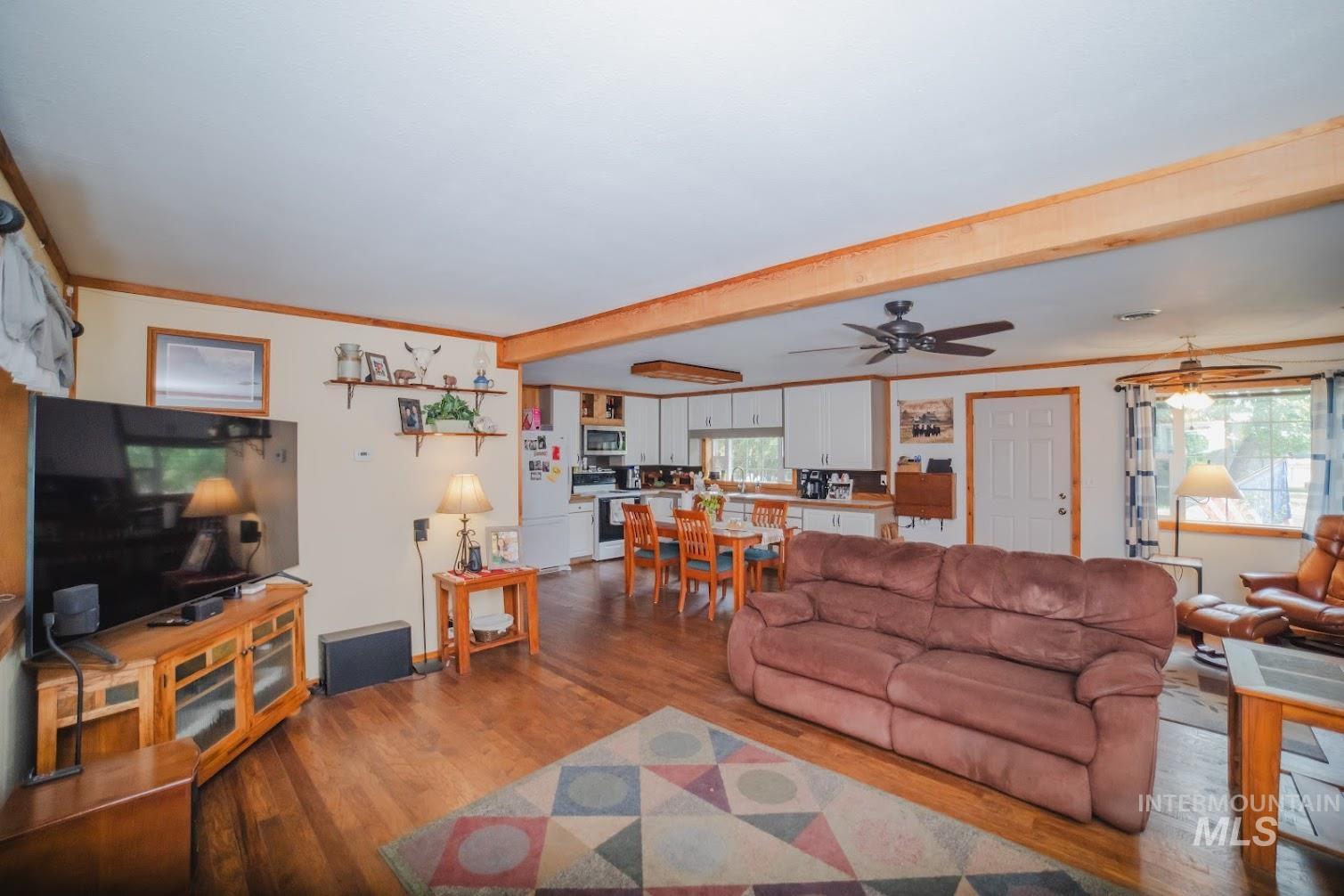 Living area with crown molding, wood finished floors, beam ceiling, and ceiling fan