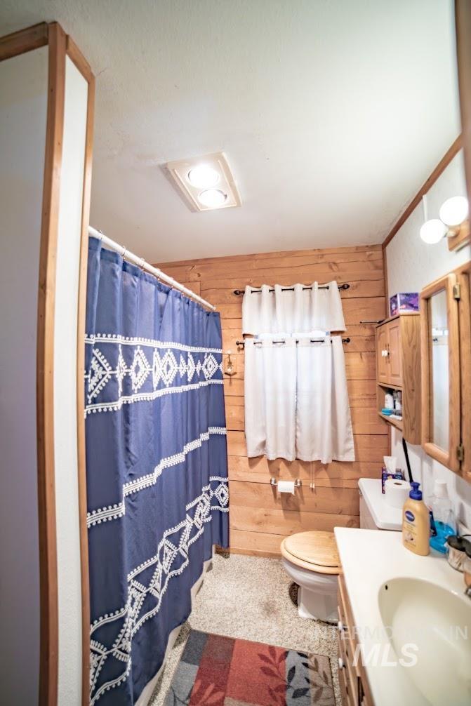 Full bathroom with wood walls, vanity, and a shower with curtain