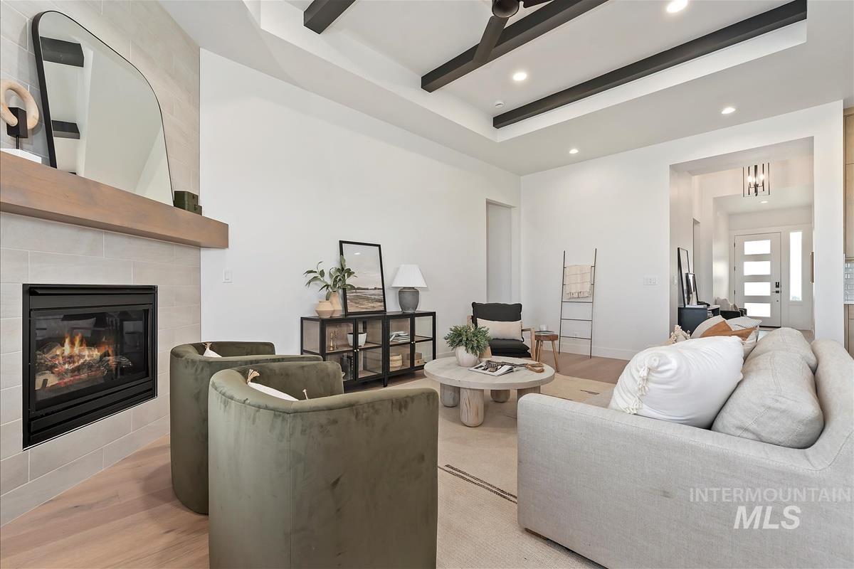 Living room featuring light wood finished floors, a raised ceiling, a fireplace, and recessed lighting