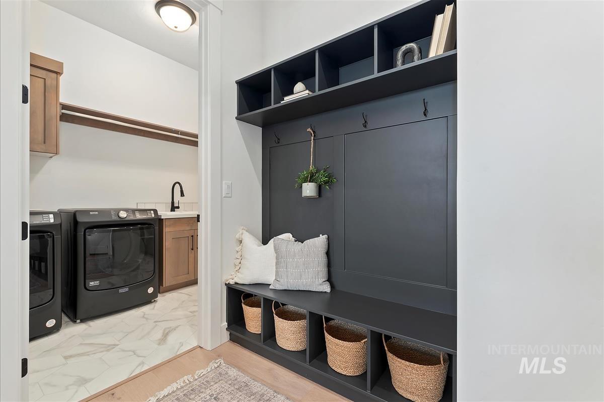 Mudroom featuring light marble finish floors and washer and dryer