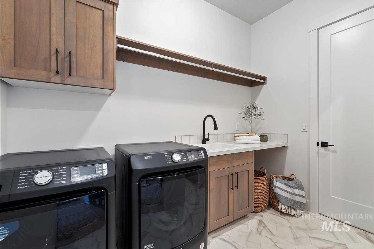 Washroom with light marble finish floors, cabinet space, and washing machine and dryer