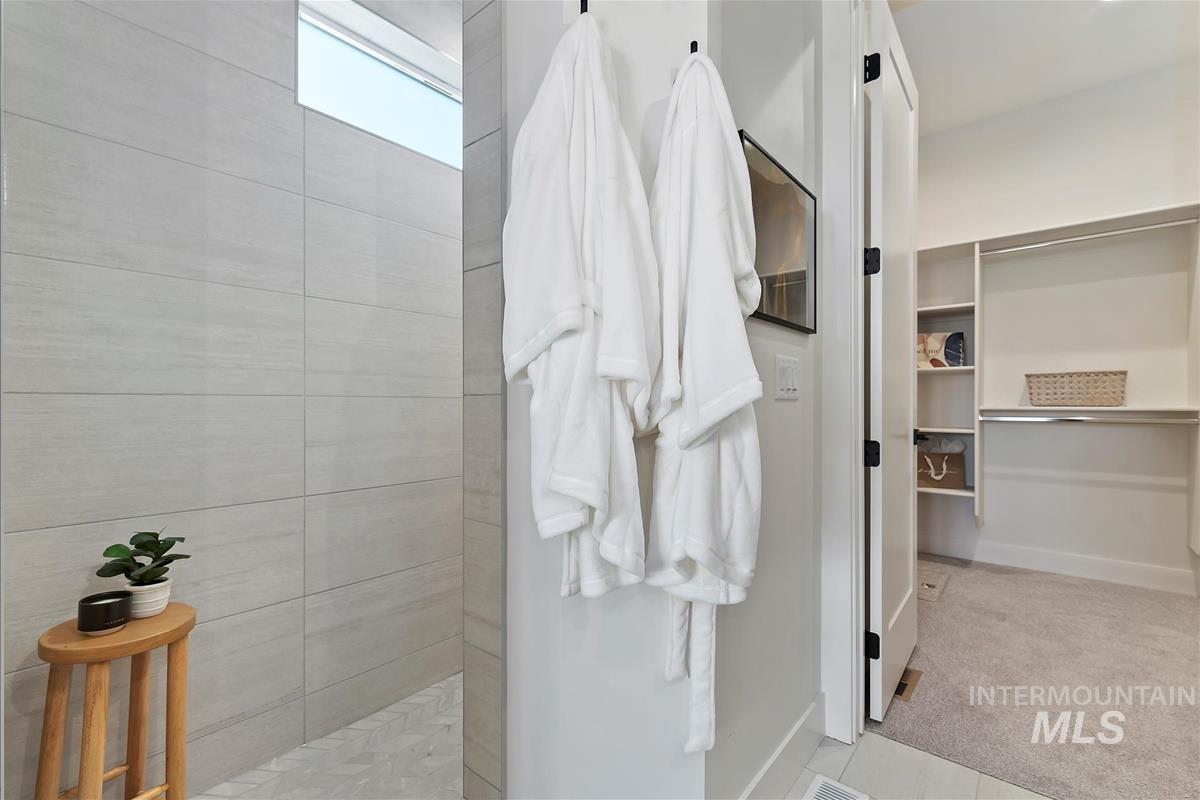 Full bathroom featuring a walk in shower, a walk in closet, and light tile patterned flooring