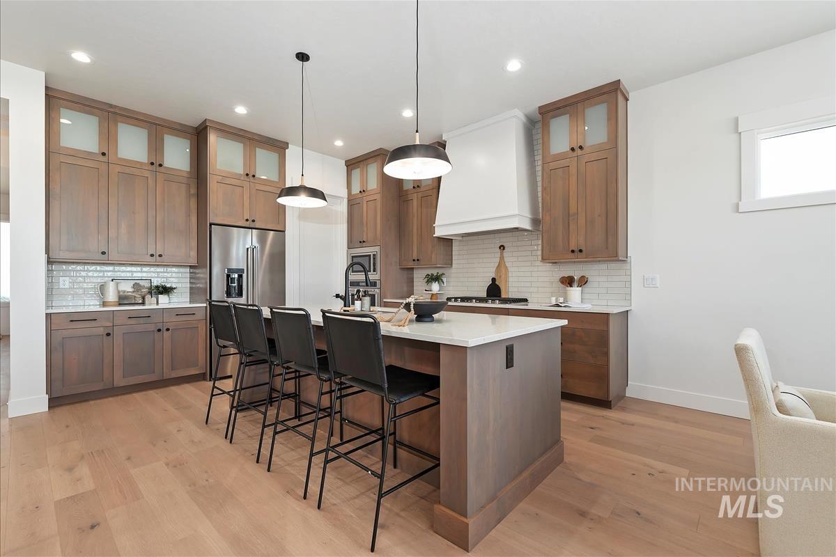 Kitchen featuring a kitchen breakfast bar, a kitchen island with sink, backsplash, pendant lighting, and recessed lighting