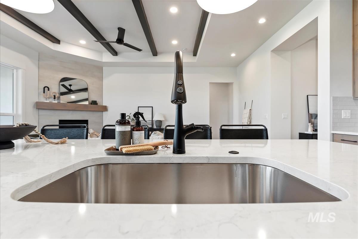 Kitchen featuring light stone countertops, open floor plan, beam ceiling, recessed lighting, and tasteful backsplash