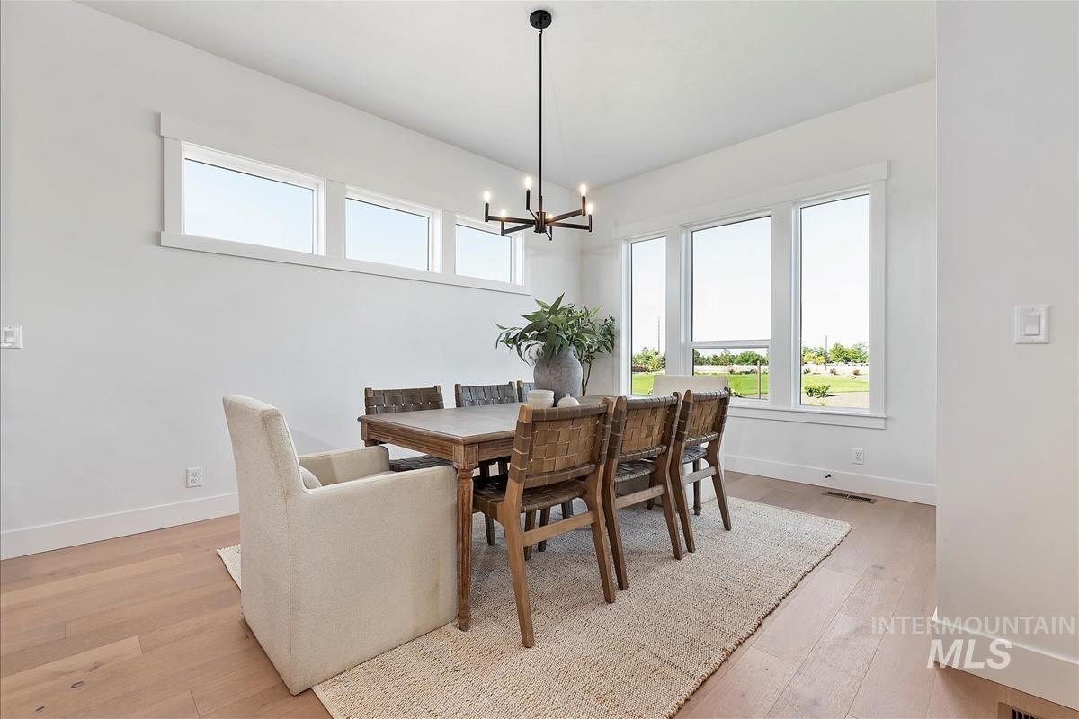 Dining space with light wood-style flooring, plenty of natural light, and a chandelier