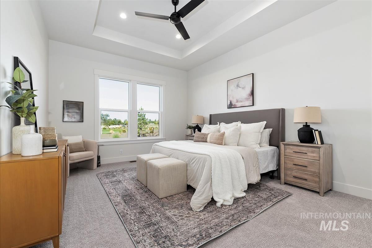 Bedroom with a tray ceiling, light colored carpet, ceiling fan, and recessed lighting