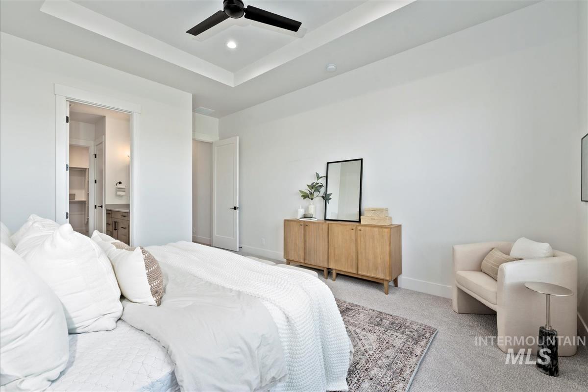 Bedroom featuring a tray ceiling, carpet floors, ensuite bath, a ceiling fan, and recessed lighting