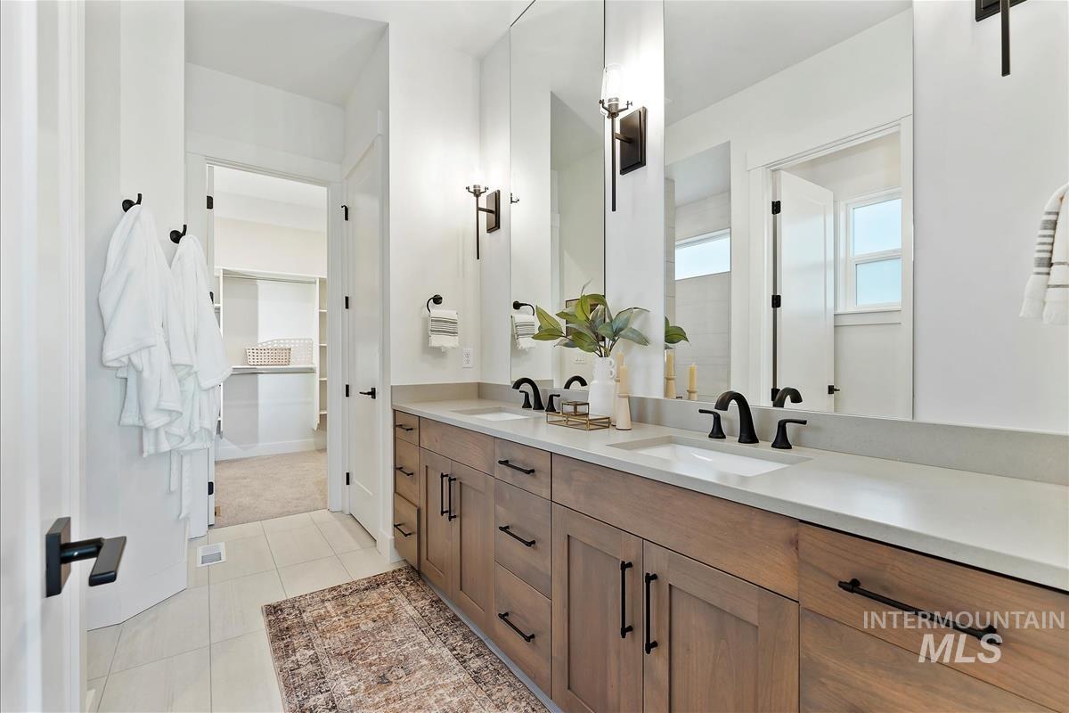 Full bathroom with double vanity, a spacious closet, and light tile patterned flooring