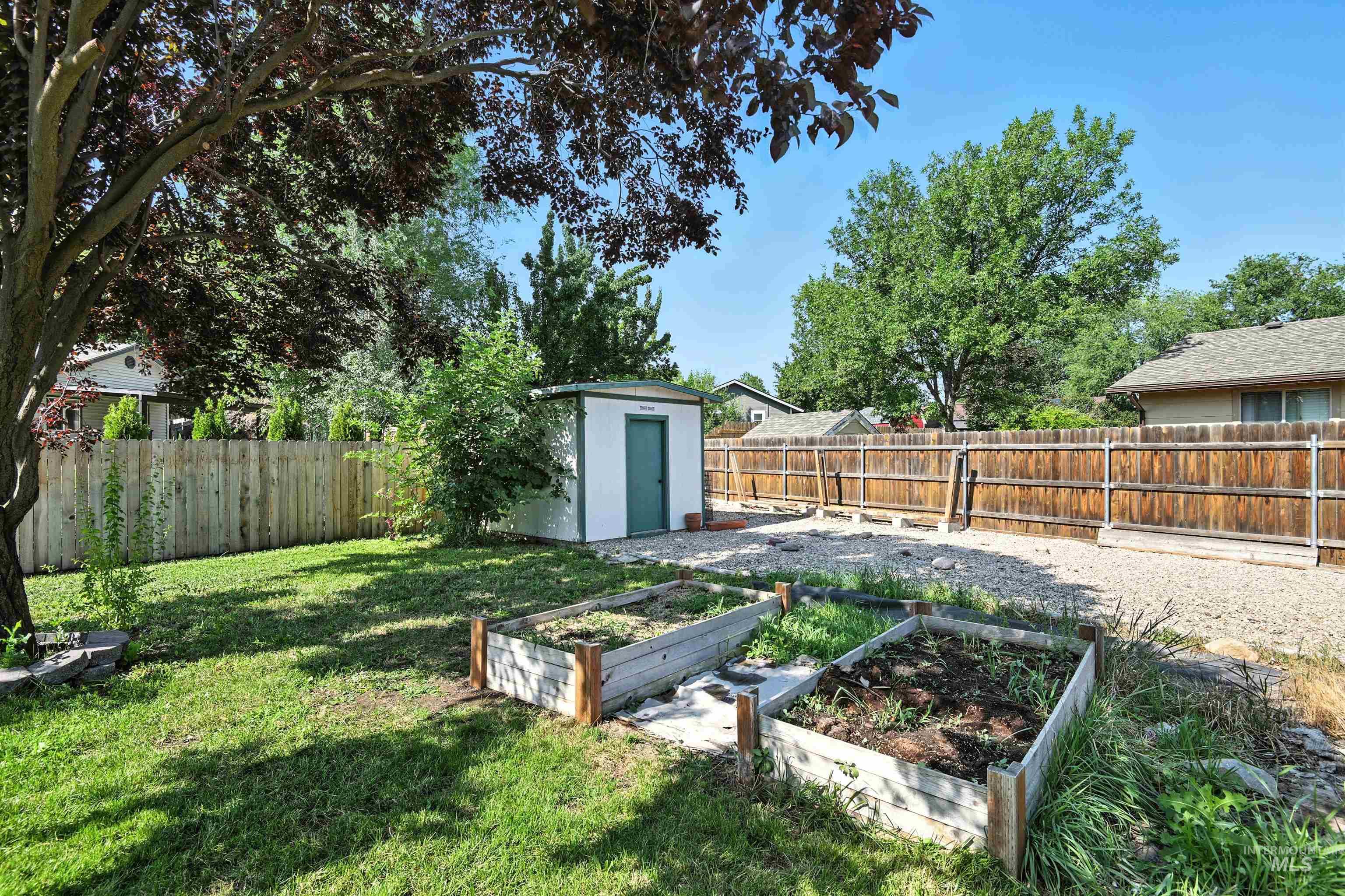 Fenced backyard with a garden and a shed
