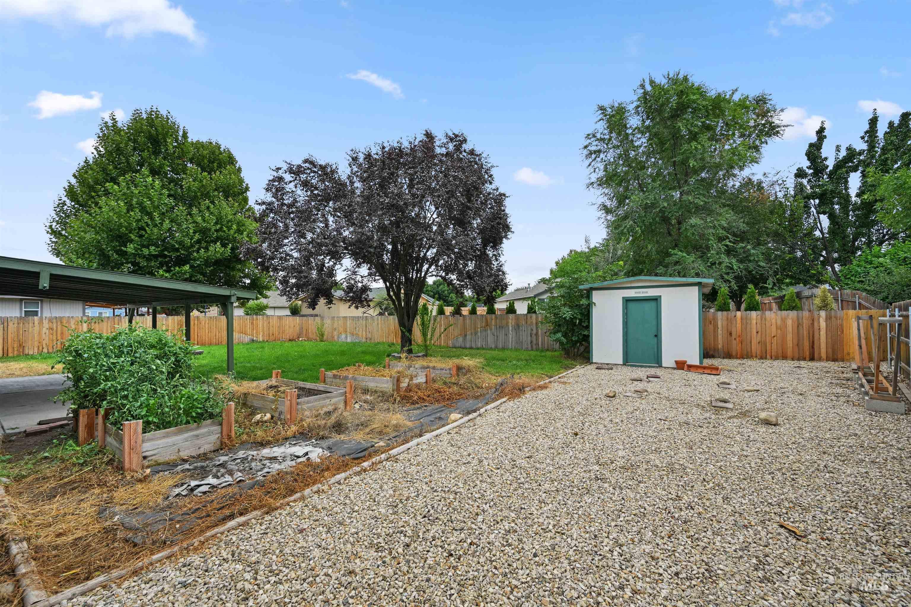 Fenced backyard featuring a vegetable garden and a shed