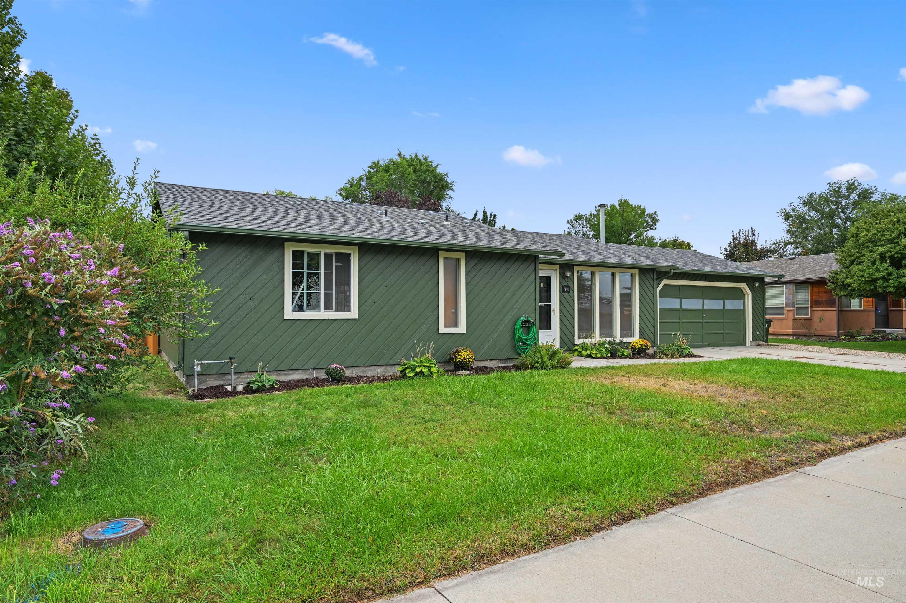 Ranch-style house featuring concrete driveway, a front lawn, an attached garage, and roof with shingles