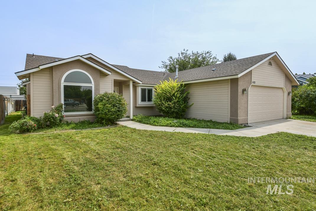 Ranch-style house featuring a front yard, a shingled roof, driveway, and an attached garage