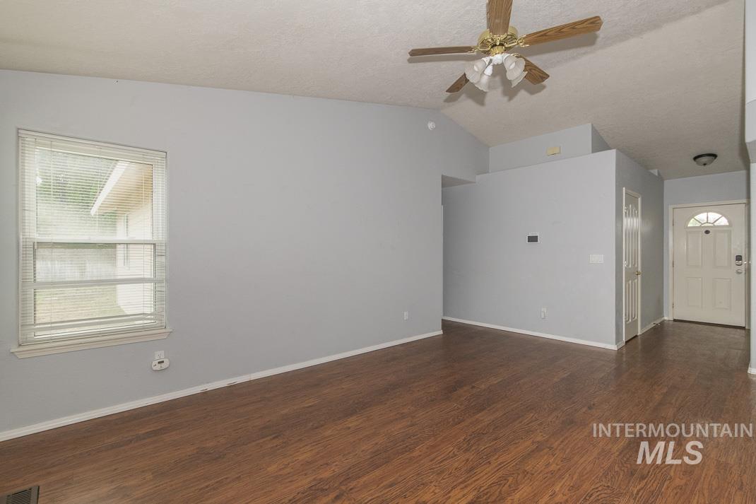 Unfurnished room featuring lofted ceiling, dark wood-style flooring, a textured ceiling, and ceiling fan