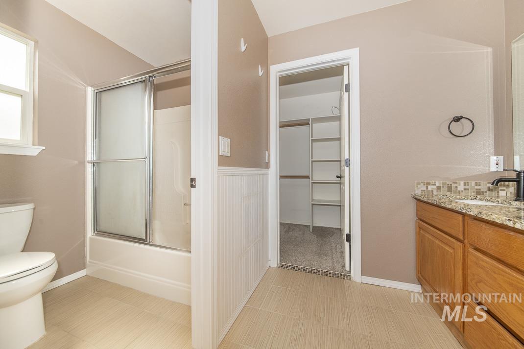 Bathroom featuring combined bath / shower with glass door, vanity, and a walk in closet