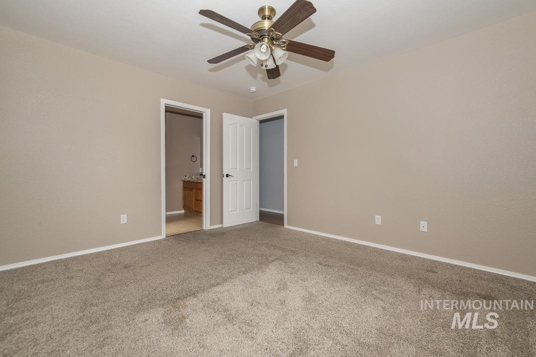 Unfurnished bedroom with light carpet, connected bathroom, and ceiling fan