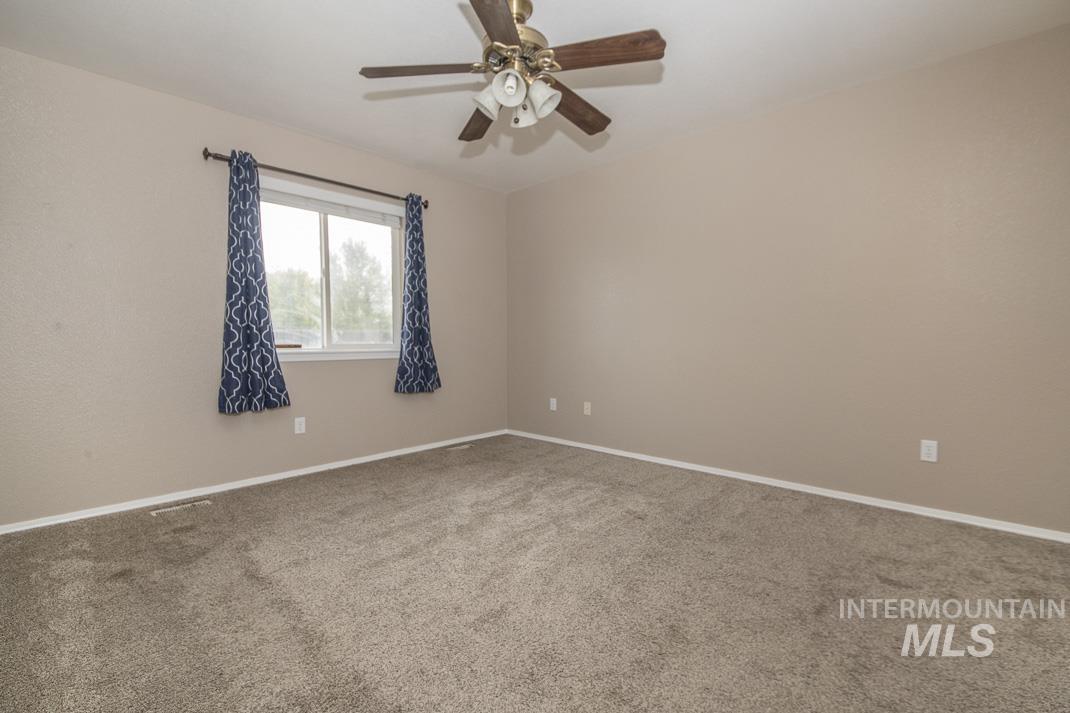 Carpeted spare room featuring baseboards and ceiling fan