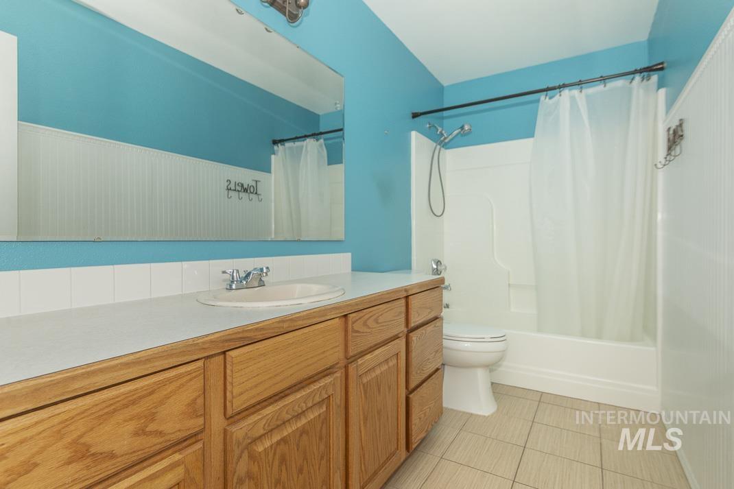 Full bath with shower / bath combo, vanity, and light tile patterned floors