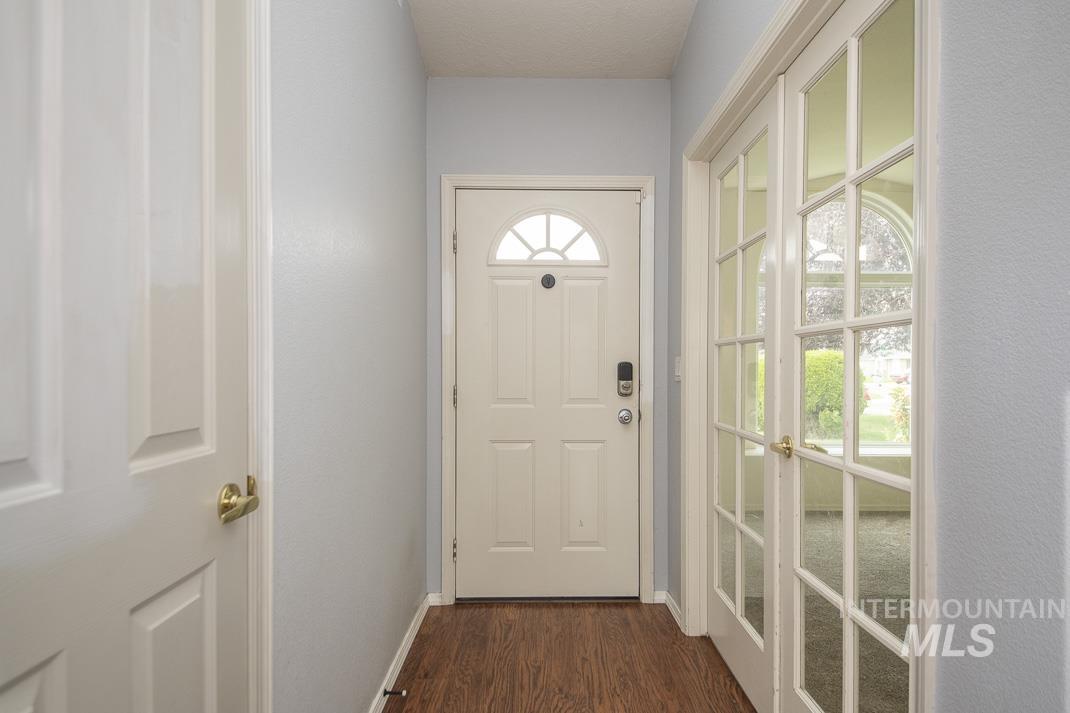 Doorway with wood finished floors and baseboards