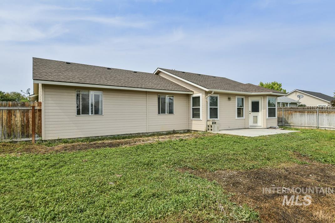 Back of property with a shingled roof, a patio area, and a fenced backyard