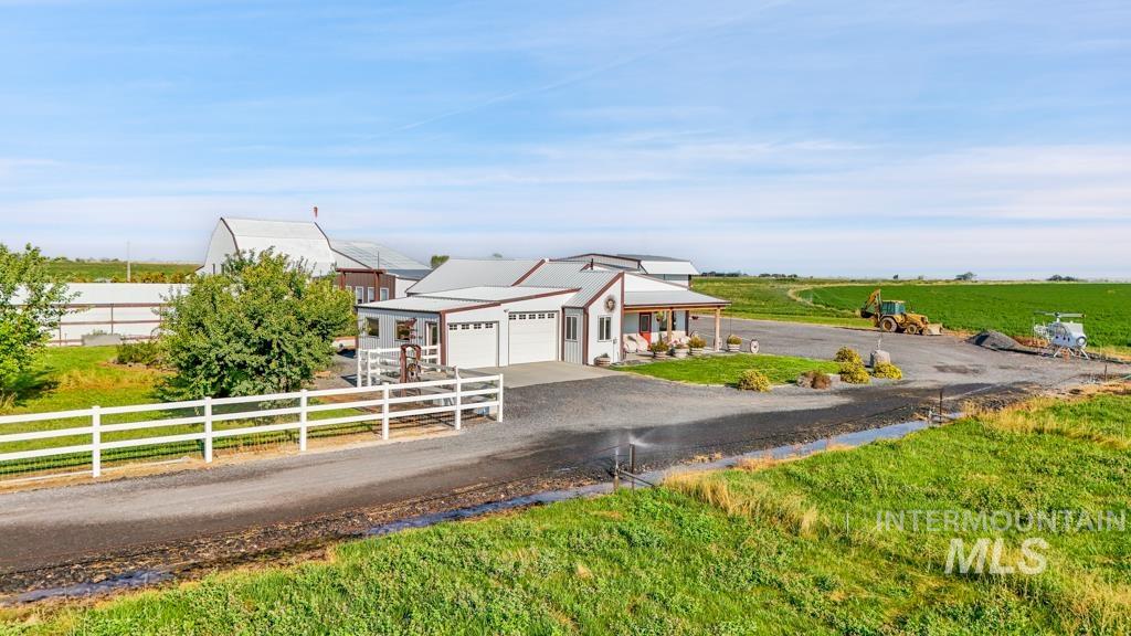 View of front of house with driveway, a garage, a rural view, and a fenced front yard