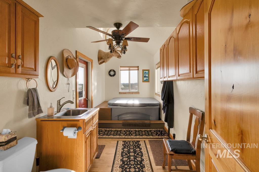 Bathroom featuring light wood-type flooring, vanity, vaulted ceiling, and a ceiling fan