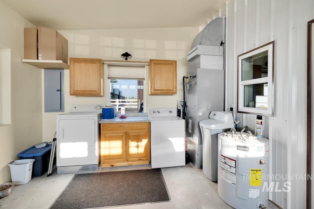 Laundry area with washer and dryer, cabinet space, electric water heater, electric panel, and heating unit