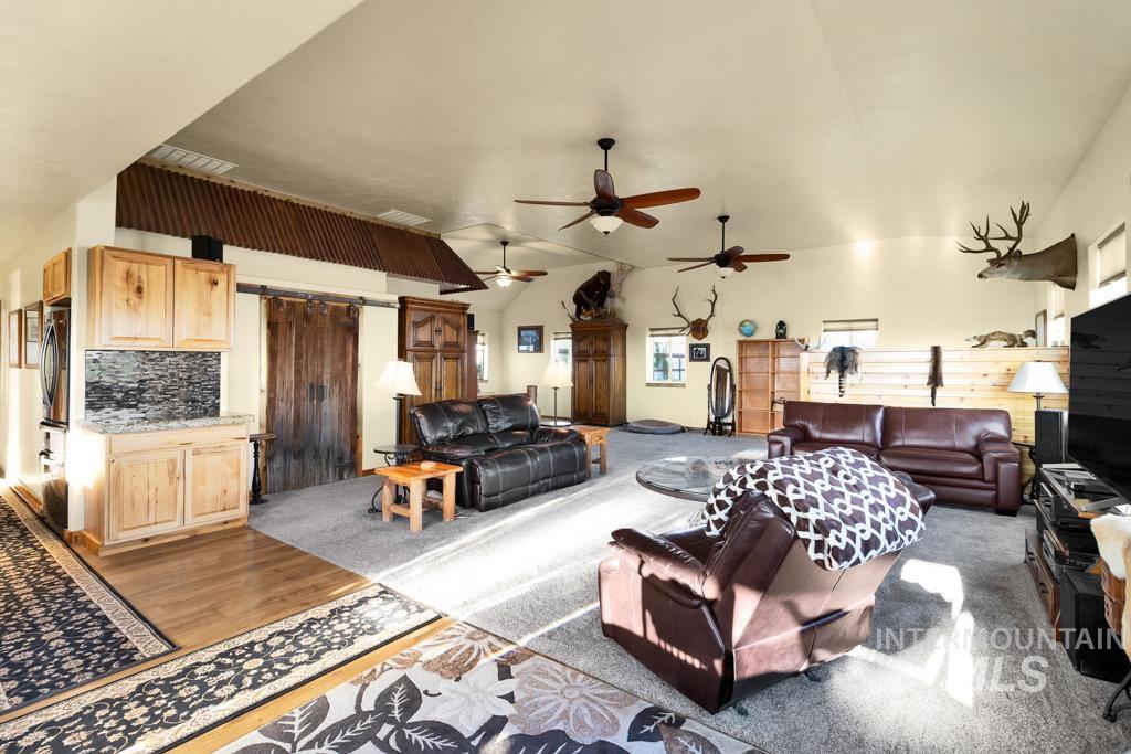 Living area featuring a barn door, vaulted ceiling, and light wood-style flooring