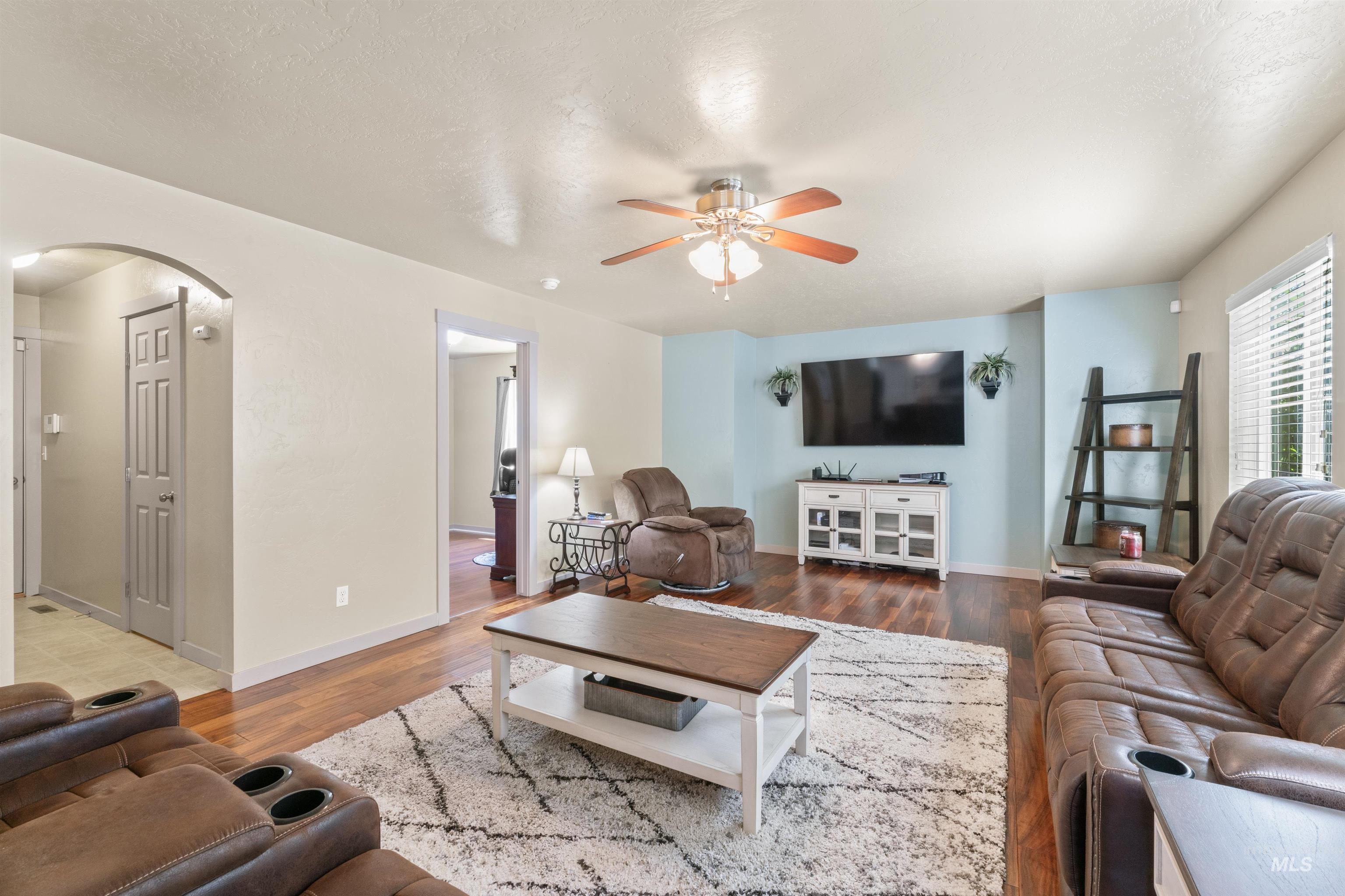 Living area with arched walkways, ceiling fan, and wood finished floors