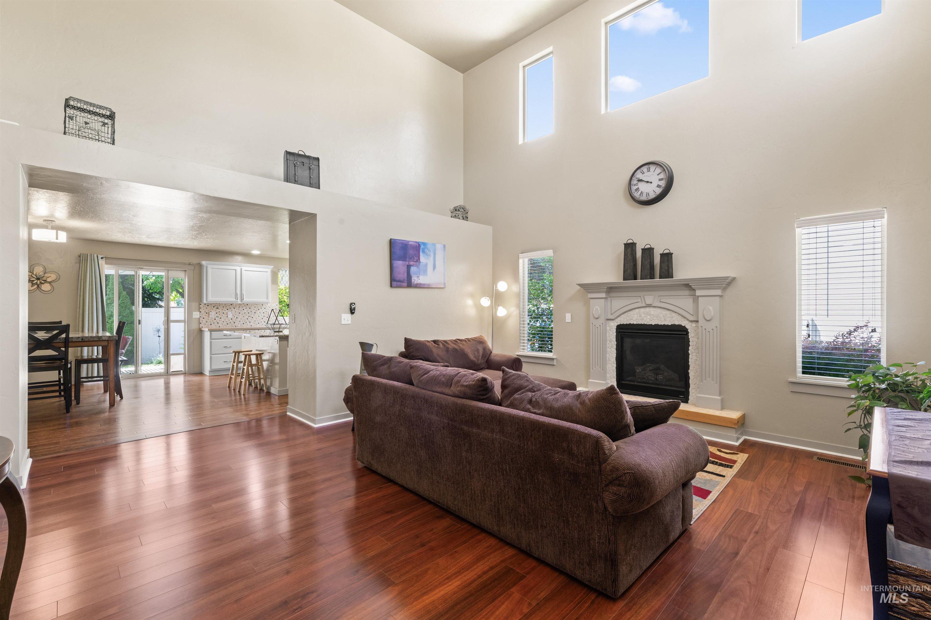 Living room featuring a high ceiling, dark wood-type flooring, and a glass covered fireplace