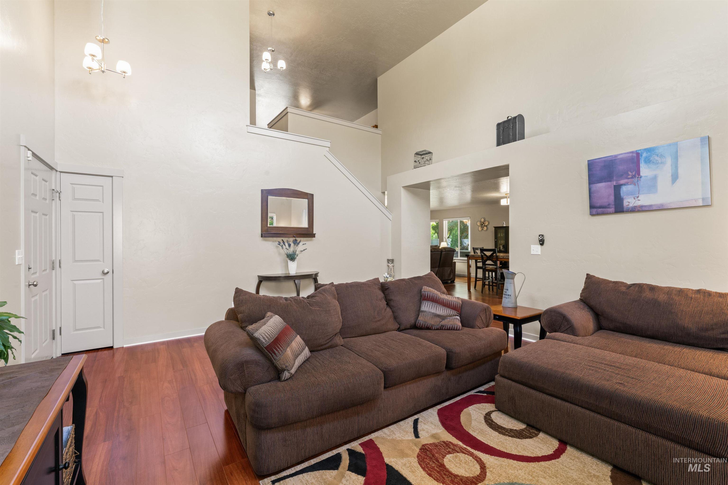 Living room with a high ceiling, wood finished floors, and stairs