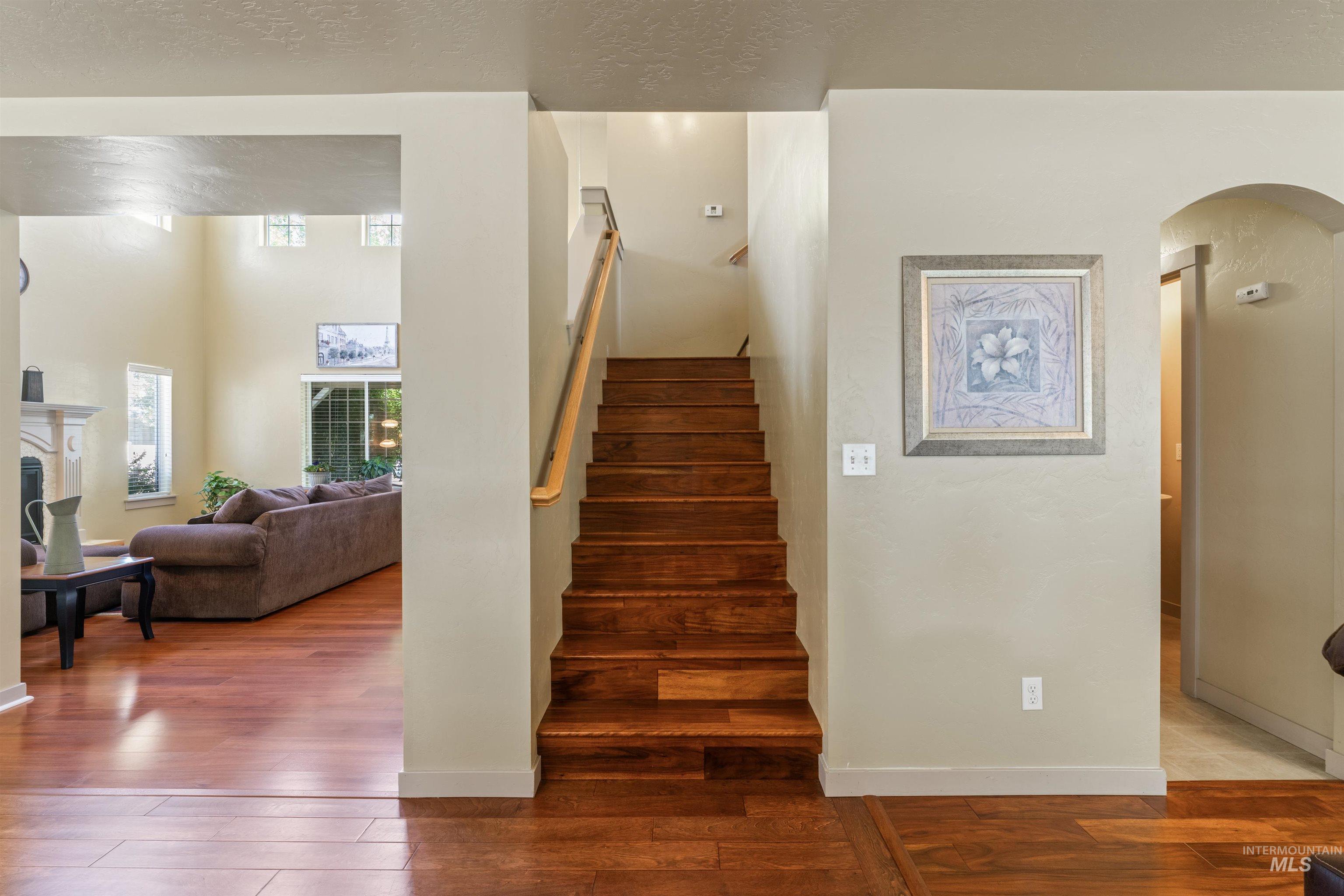 Stairs featuring arched walkways, wood-type flooring, and a fireplace