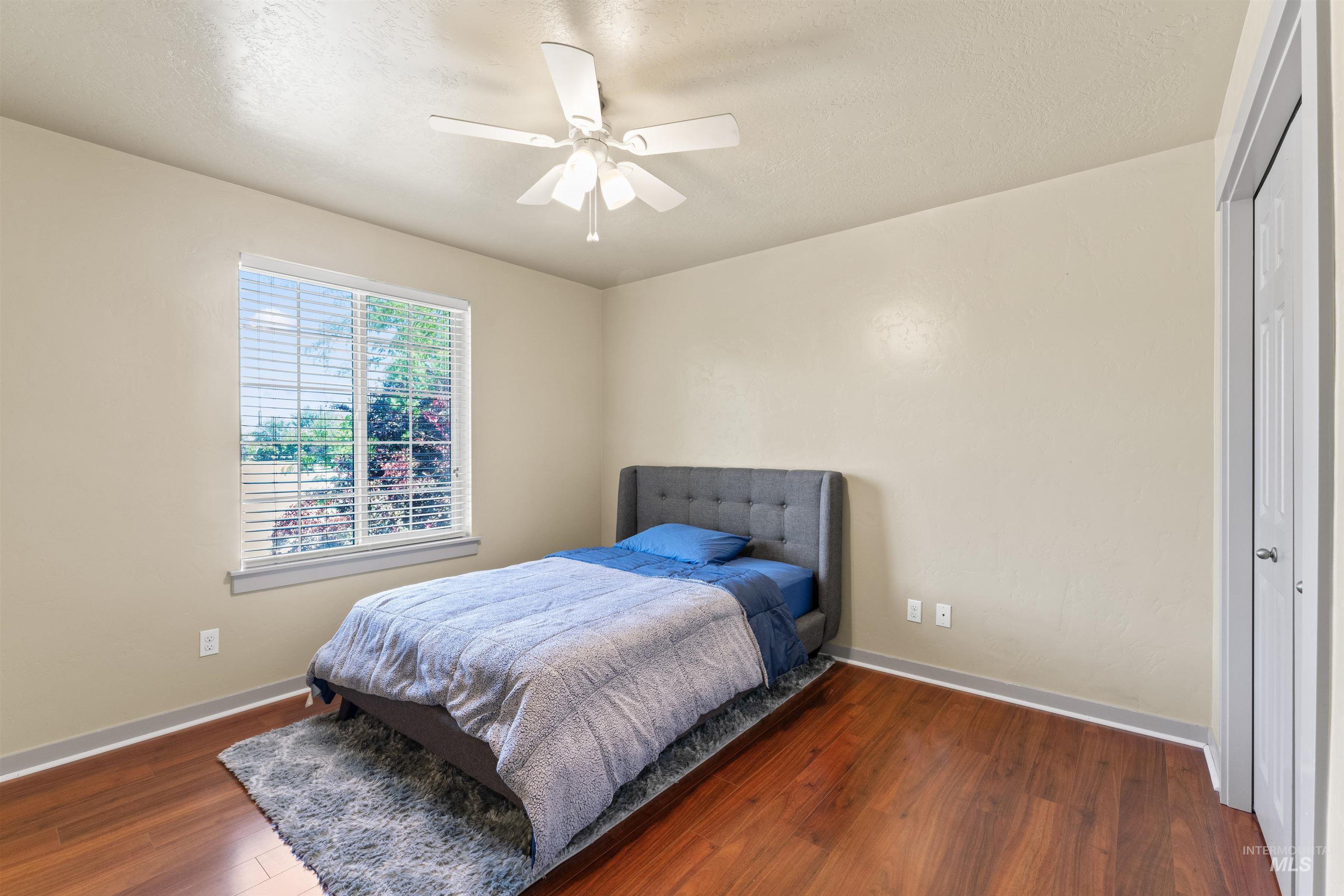 Bedroom with wood finished floors, ceiling fan, a closet, and a textured ceiling