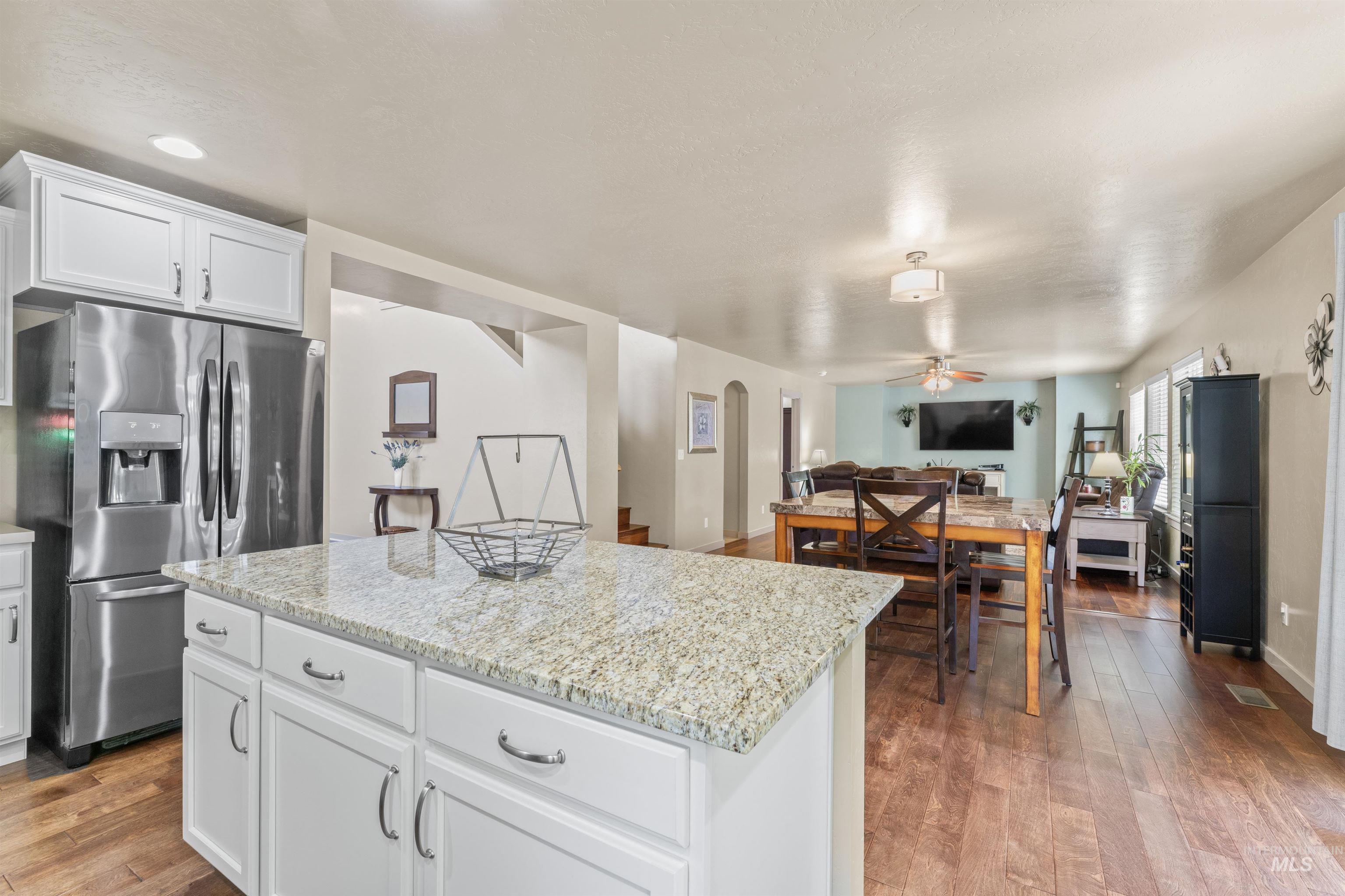 Kitchen with stainless steel fridge, a ceiling fan, open floor plan, hardwood / wood-style flooring, and a center island