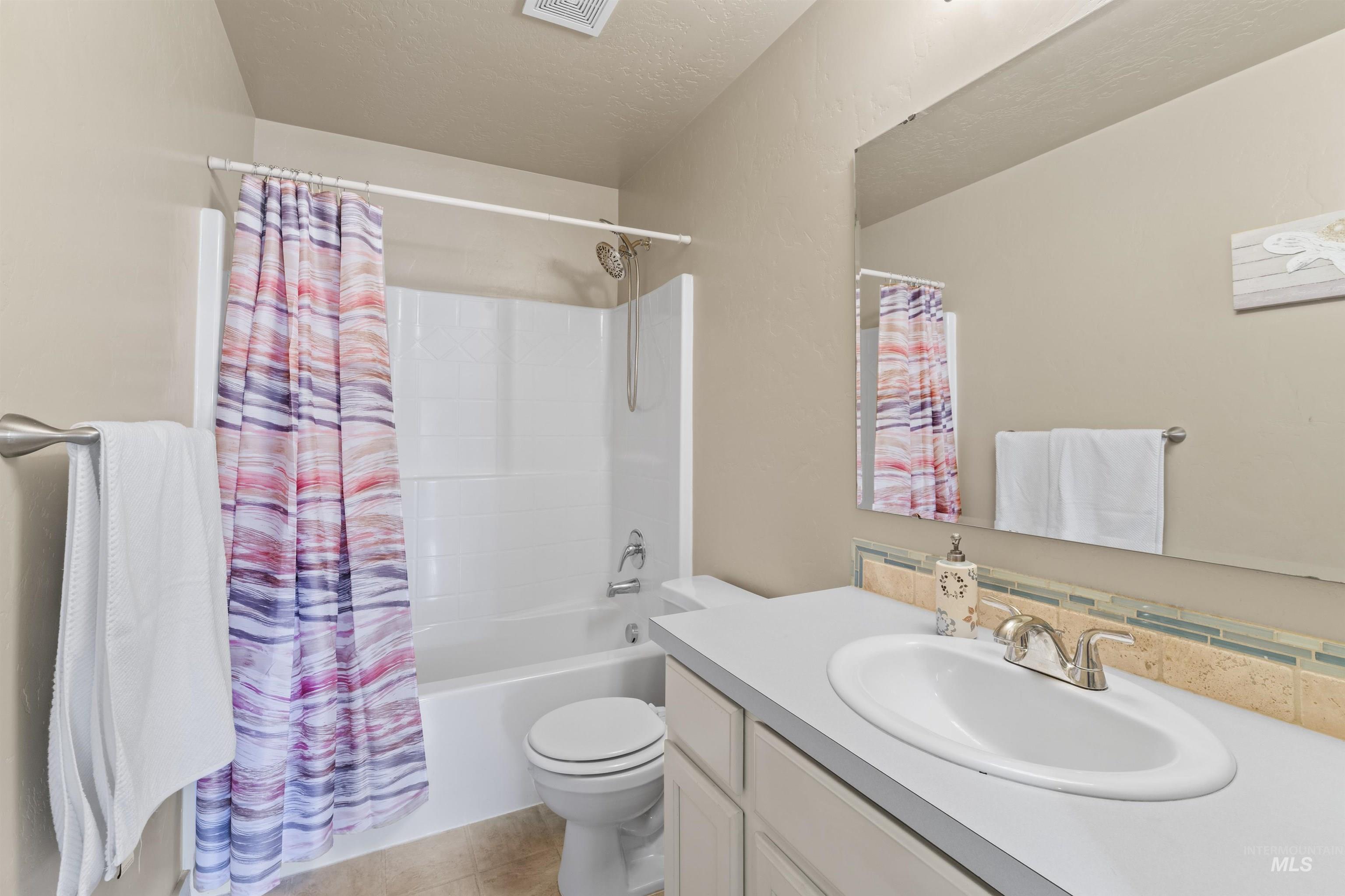 Bathroom featuring vanity, shower / bath combo with shower curtain, and tile patterned floors