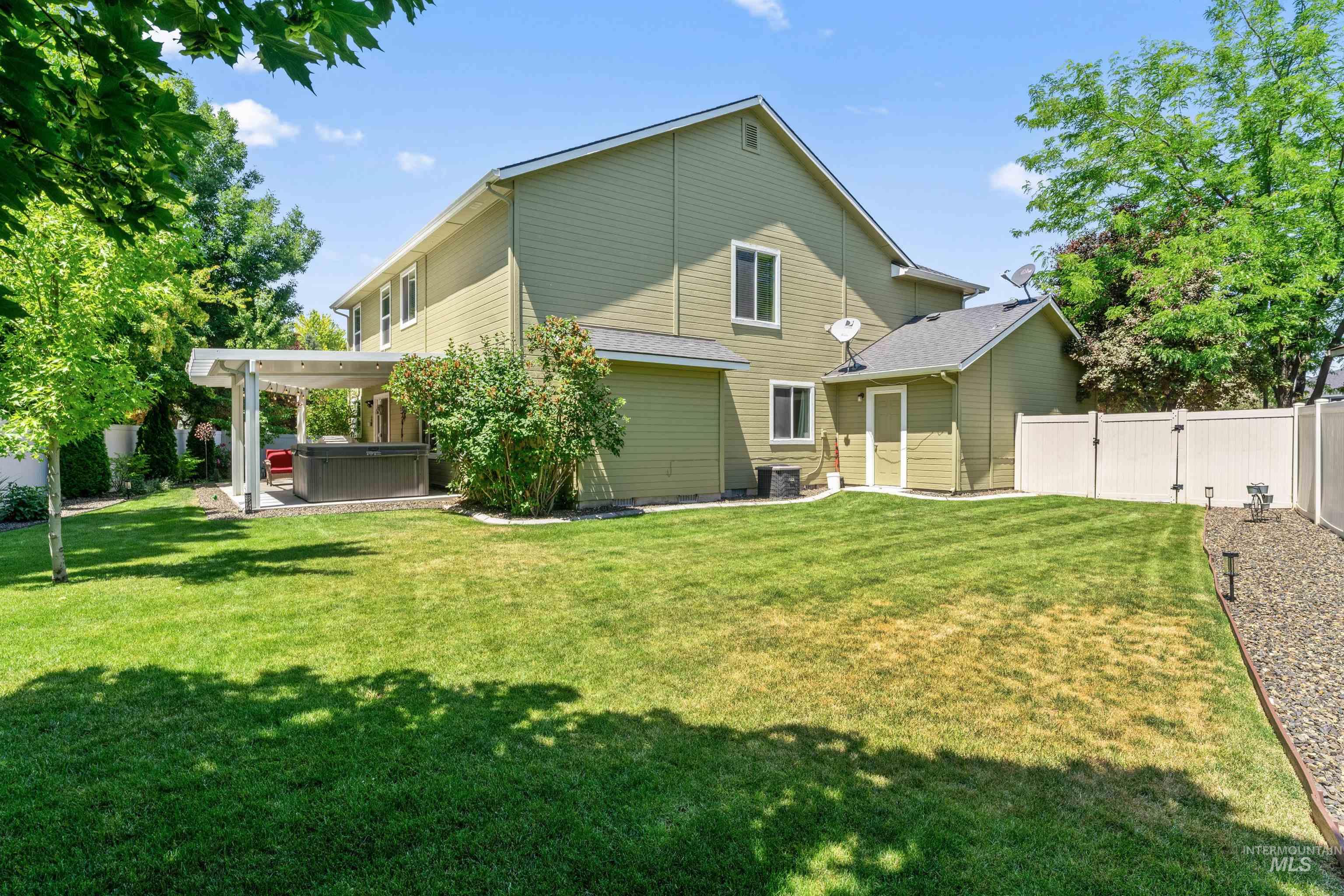 Rear view of property featuring a hot tub, a fenced backyard, and a gate
