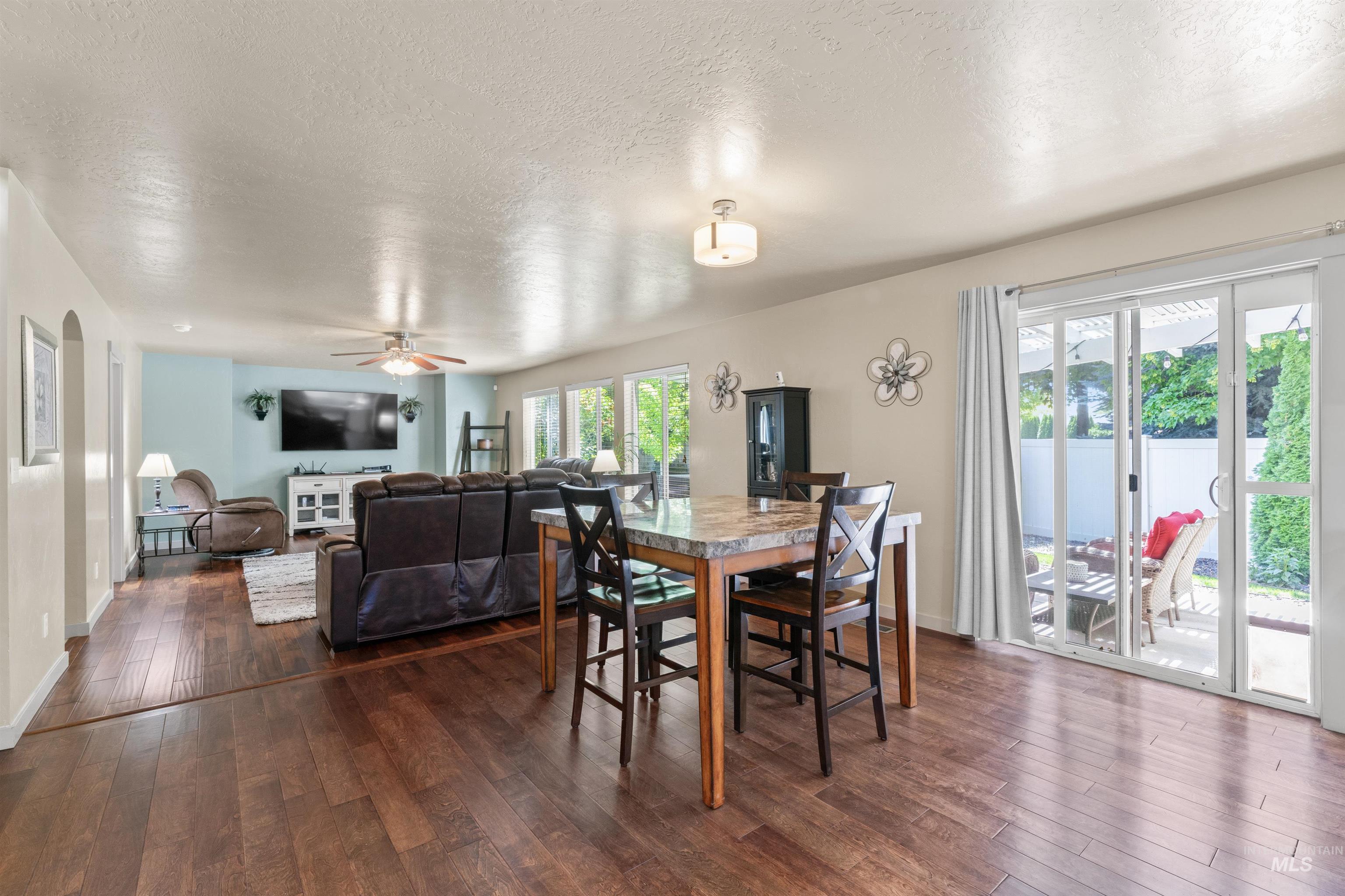 Dining space with dark wood-style floors, a textured ceiling, a ceiling fan, and arched walkways