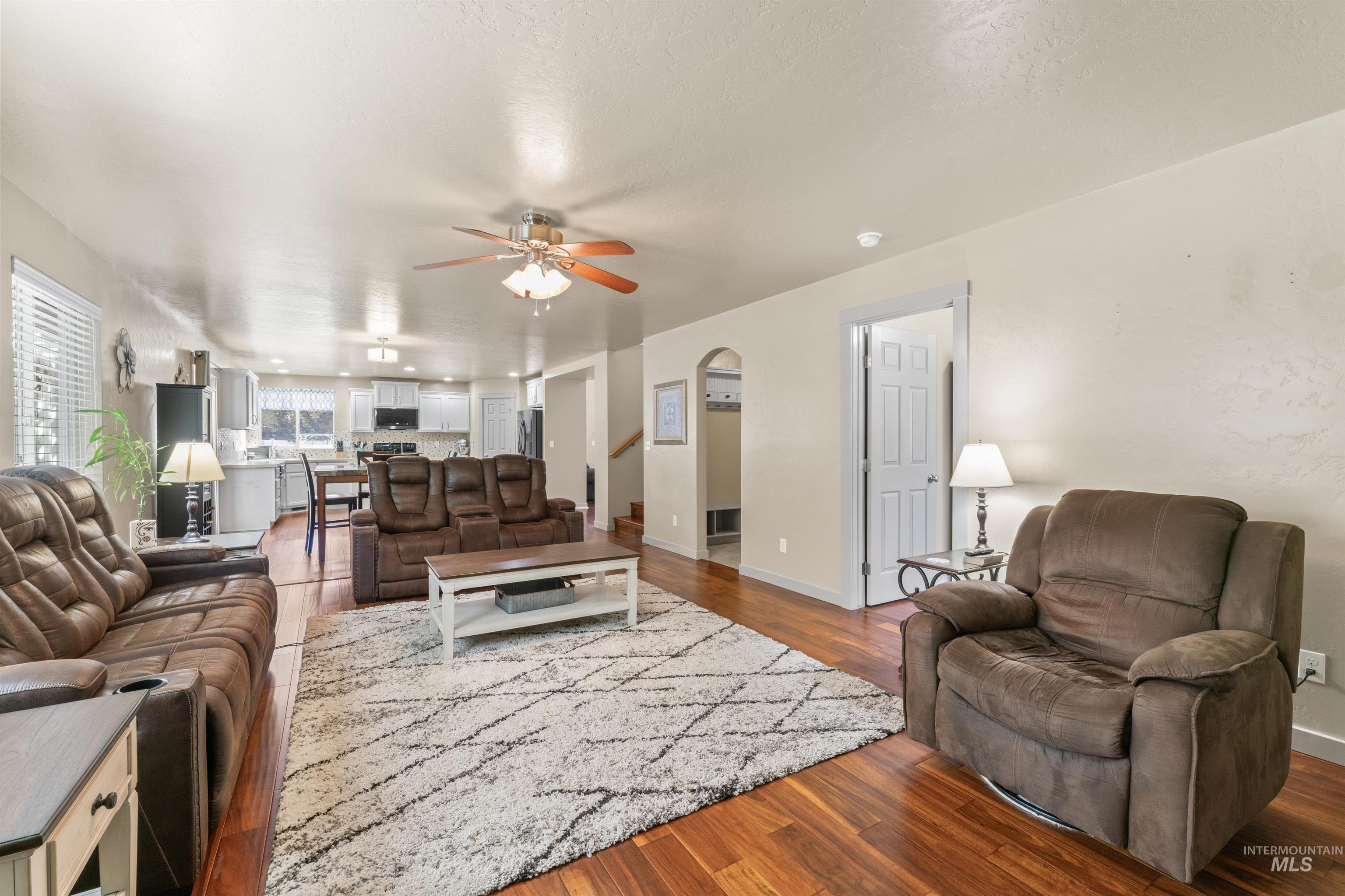 Living room featuring arched walkways, a ceiling fan, and dark wood finished floors