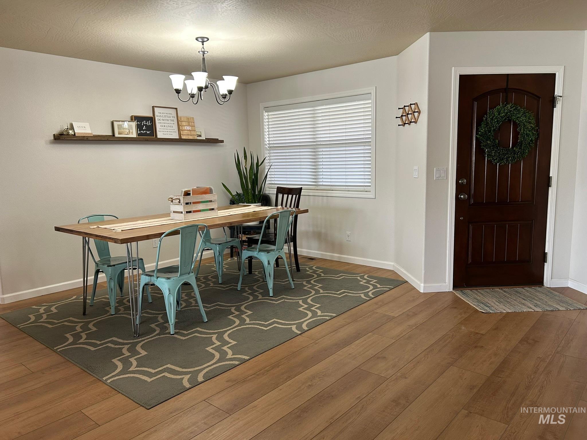 Dining area with wood finished floors, a textured ceiling, and a chandelier