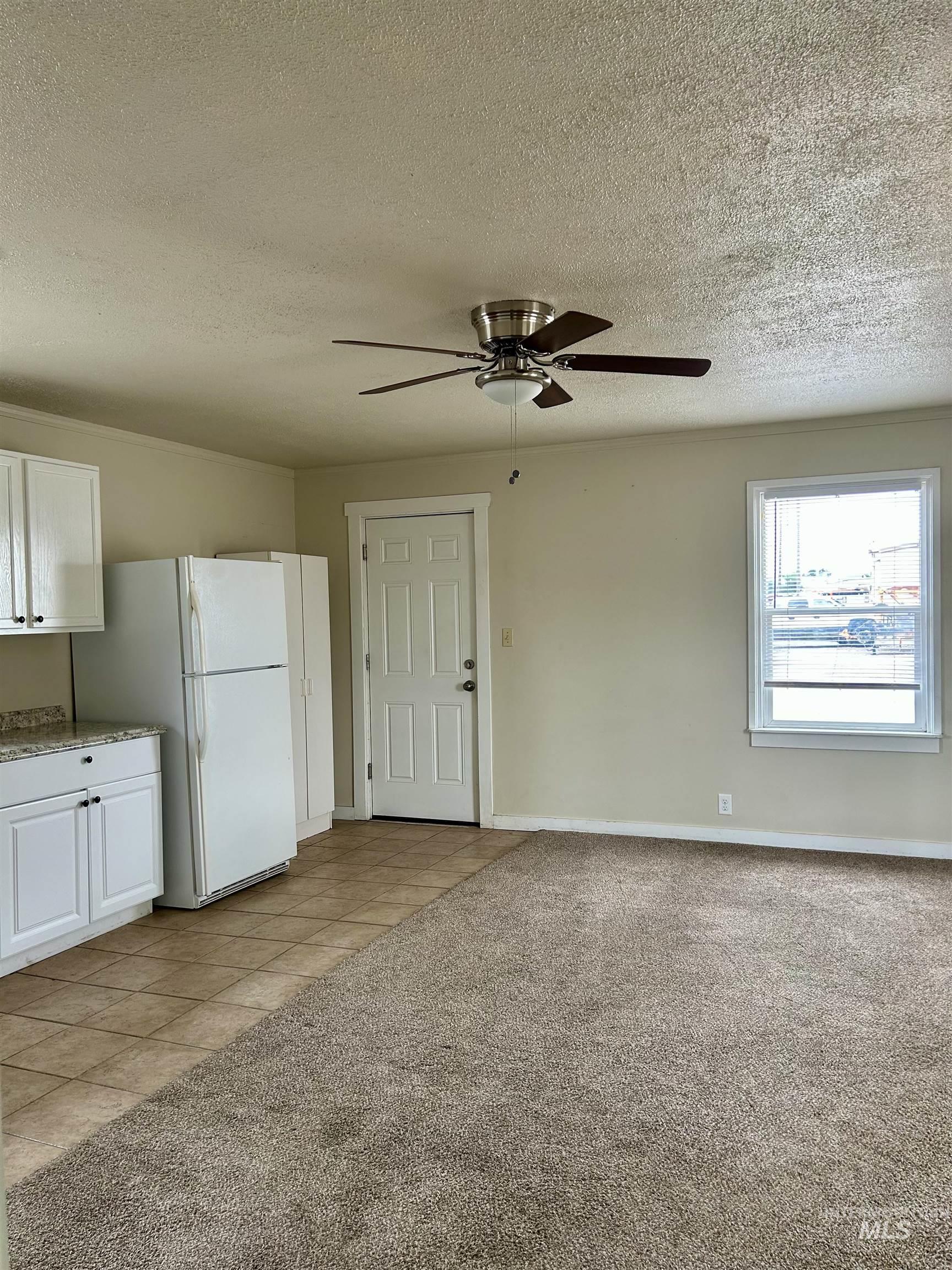 Kitchen with light carpet, freestanding refrigerator, a textured ceiling, light tile patterned floors, and white cabinets