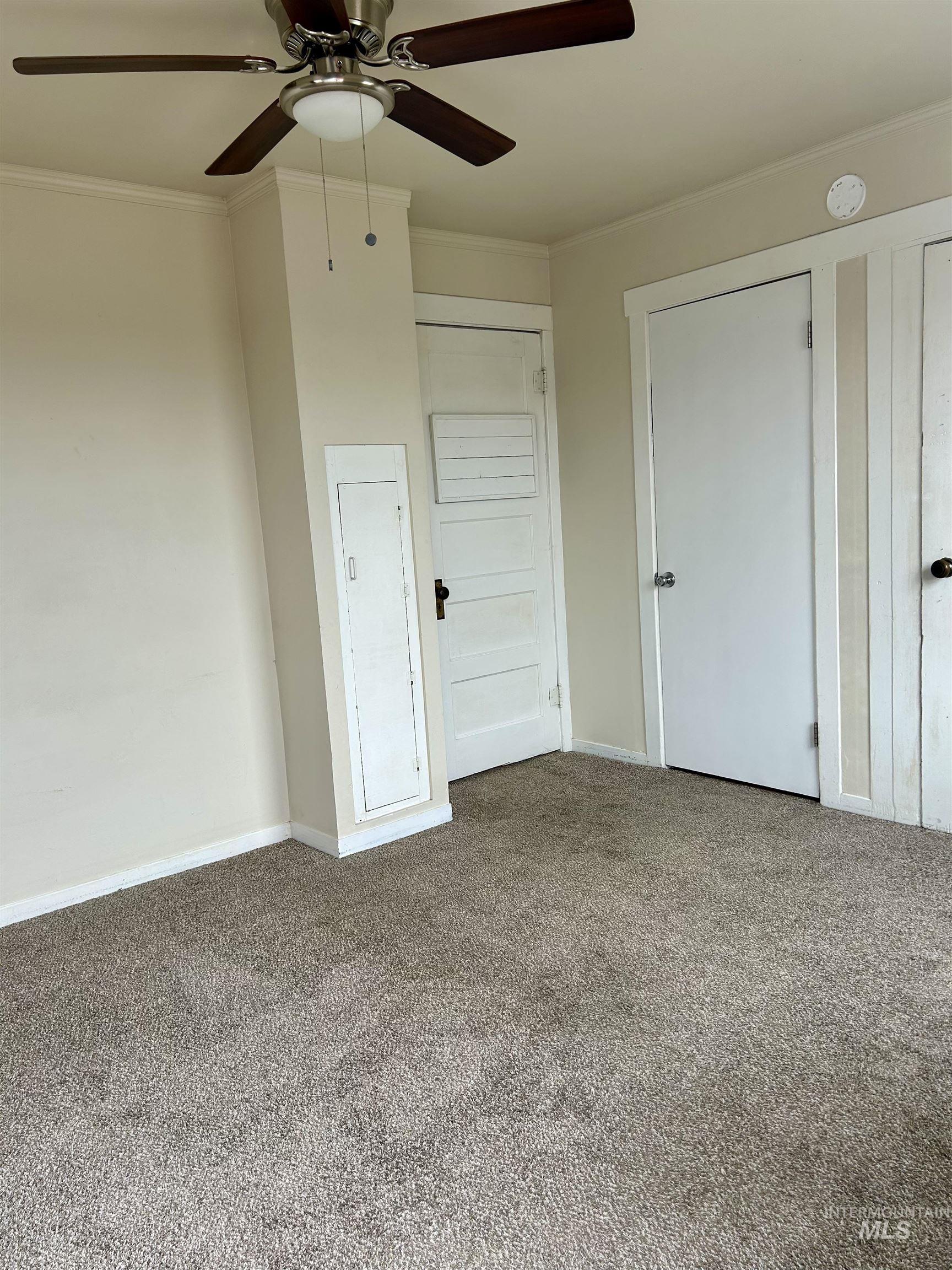 Unfurnished bedroom featuring crown molding, carpet flooring, and a ceiling fan